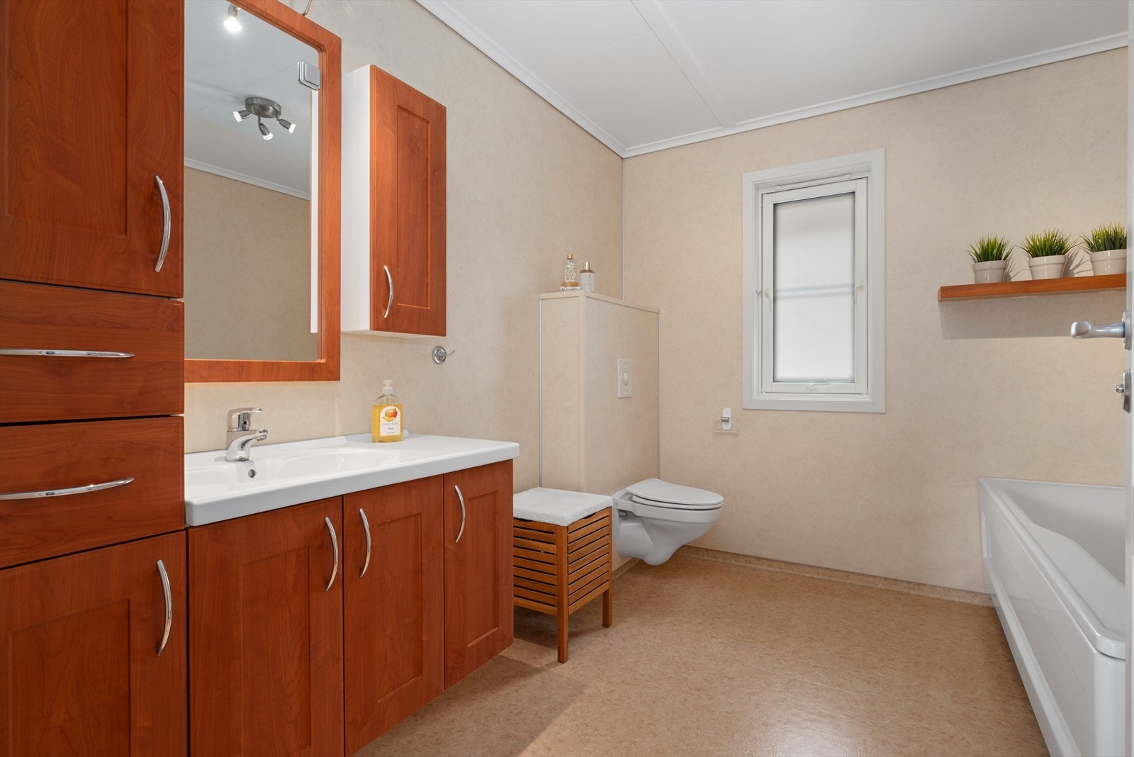 Bad med servantskap, vegghengt toalett, badekar og dusjhjørne. Varme i gulv. Galleribilde