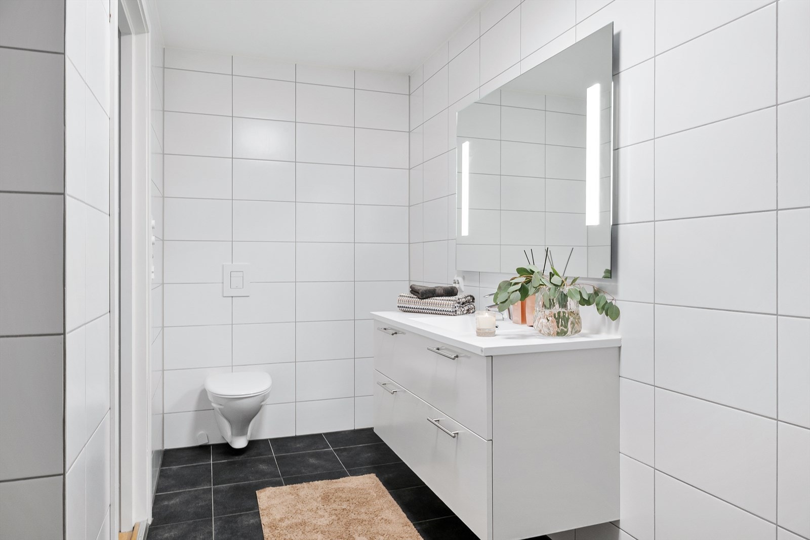 Baderommet kombinerer stilrene overflater med praktisk funksjonalitet. Galleribilde