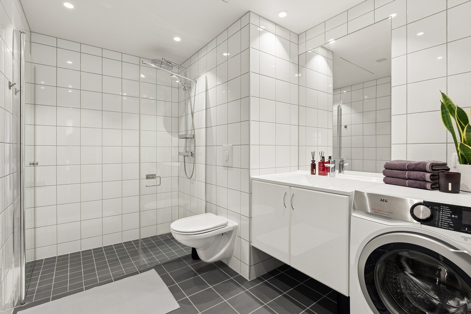 Badet er stort og tidløst innredet med grå fliser på gulvet og hvite fliser på vegg. I gulvet har man også varmekabler for ekstra komfort. Galleribilde