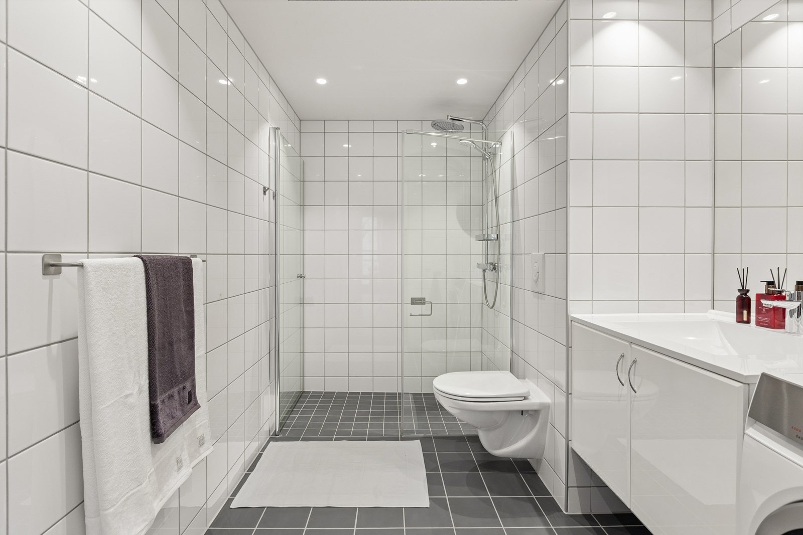 Badet er ellers utstyrt med stort dusjhjørne, vegghengt toalett og baderomsinnredning med nedfelt servant. I tillegg har man opplegg for vaskemaskin. Galleribilde