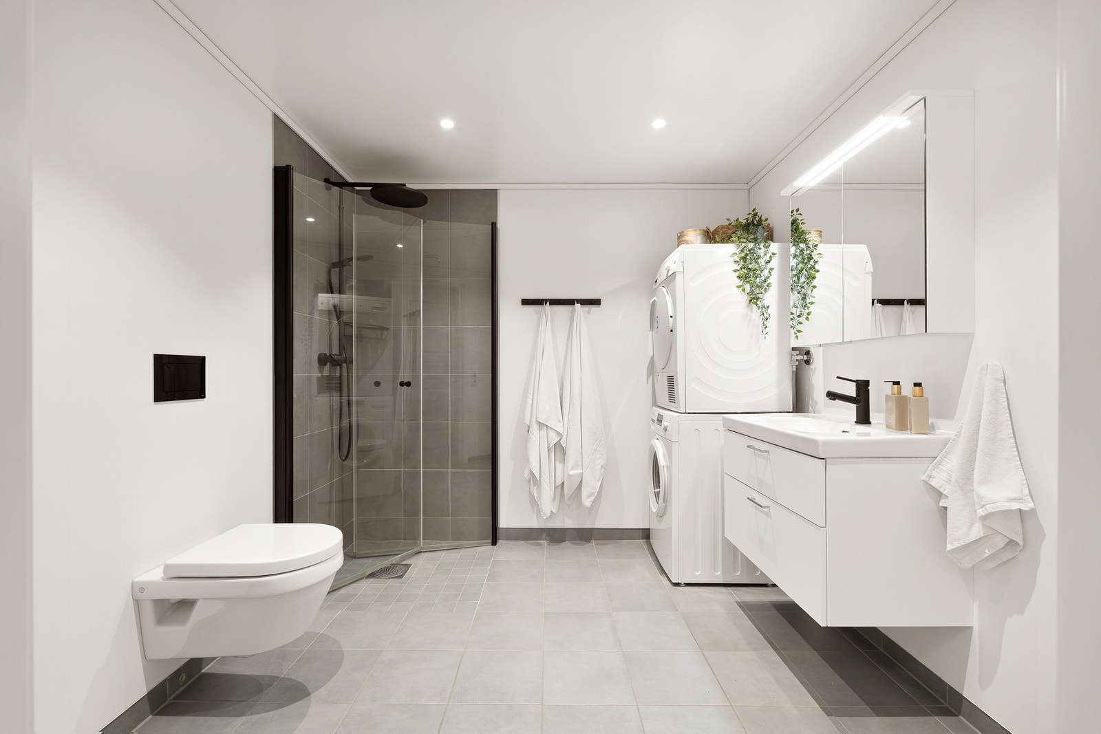 Delikat og flislagt bad med stor dusj og sort blandebatteri og detaljer. Galleribilde