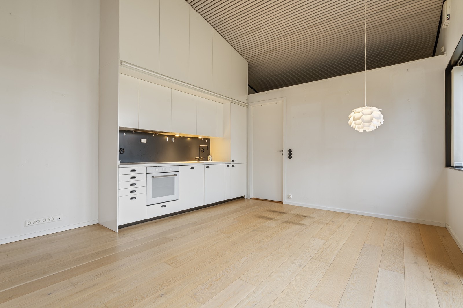 Kjøkkenet er utformet med rene linjer, rikelig skapplass og integrert arbeidsflate som bidrar til et helhetlig og ryddig preg. Kjøkkeninnredning med skap i høyden. Med stige på skinne for å nå de høyeste skapene. Galleribilde