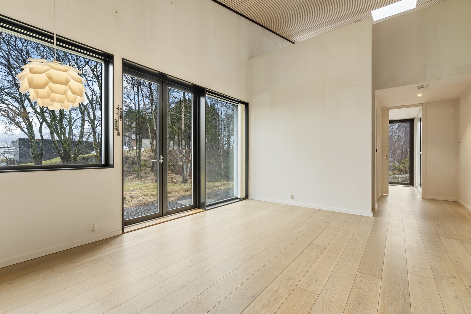 Boligen byr på en lys og luftig stue/kjøkken-sone med imponerende takhøyde og store vindusflater som slipper inn rikelig med naturlig lys. Galleribilde