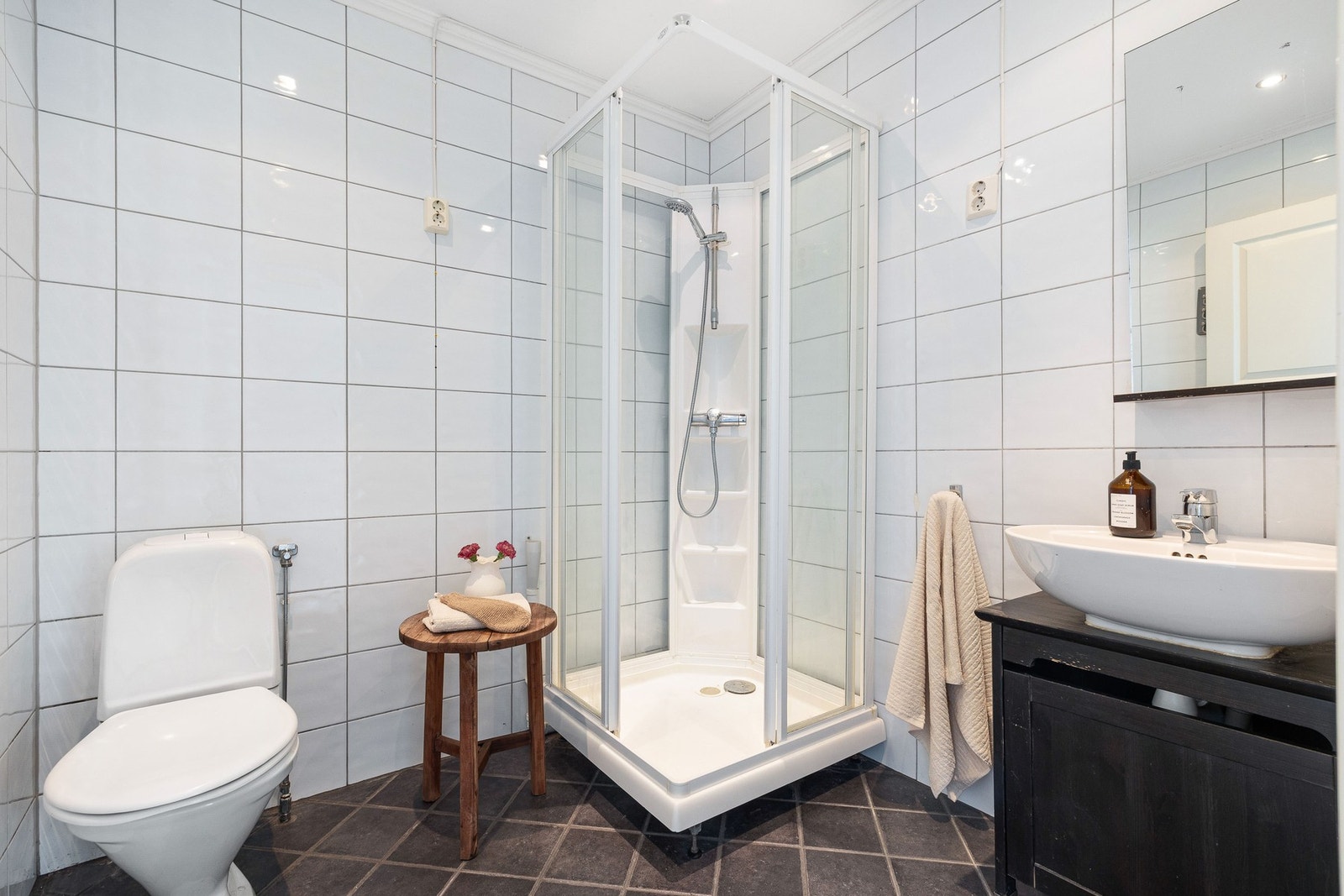 Badet har moderne innredning, gulvmontert toalett, dusjkabinett og opplegg for vaskemaskin. Galleribilde