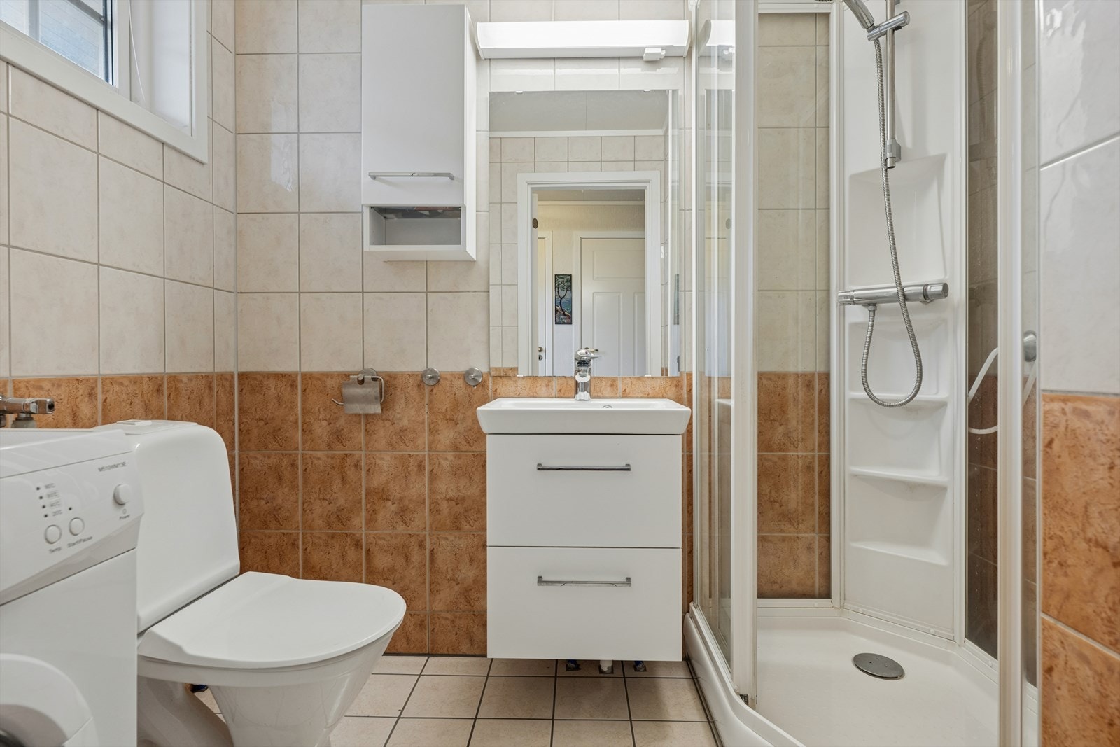 Badet er utstyrt med servant i servantskap, toalett og dusjkabinett. Galleribilde