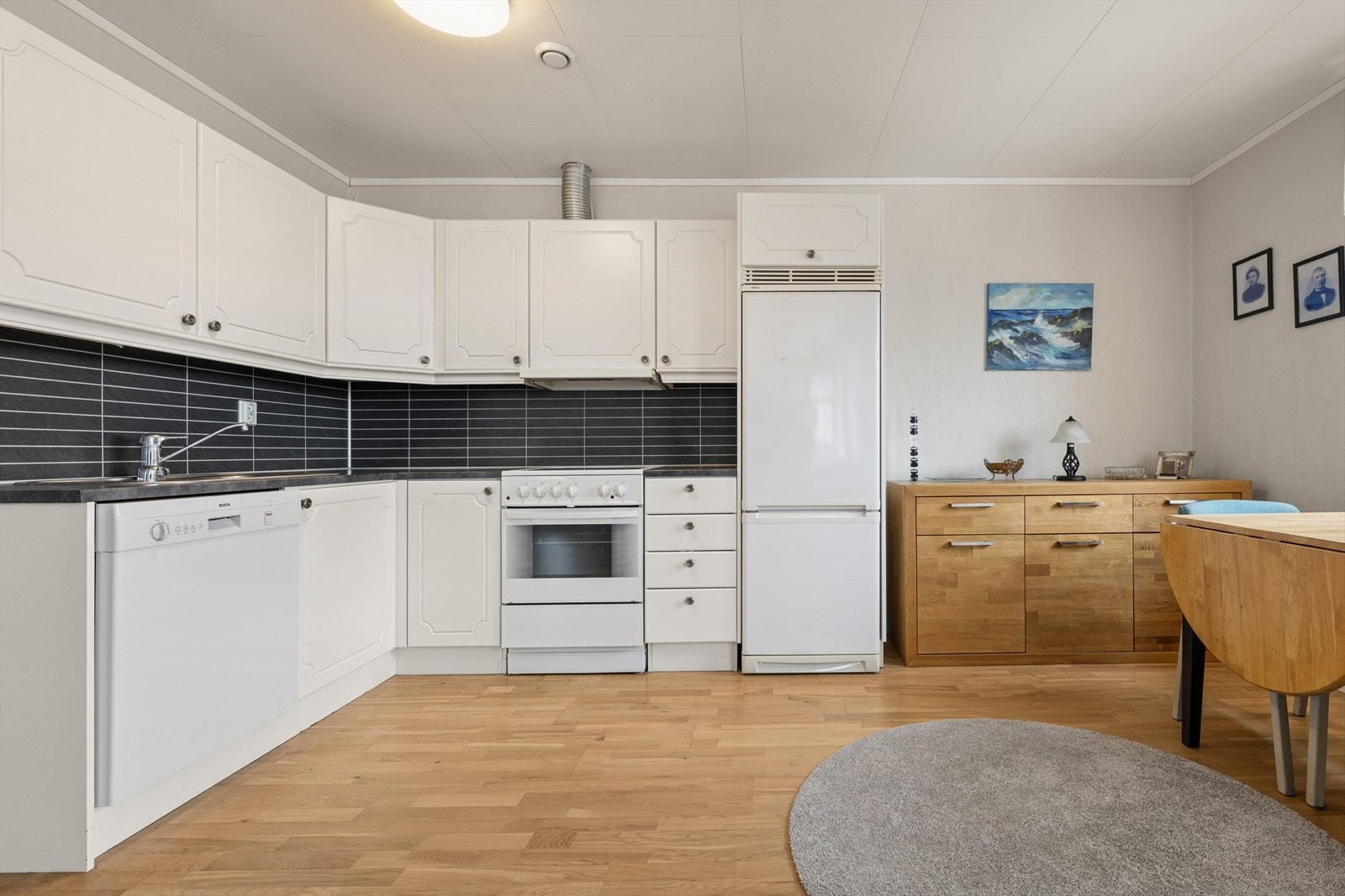 Kjøkkenet har en hvit, profilert innredning med god benke- og skapplass. Det er plass og opplegge for oppvaskmaskin, ovn og kjøl/frys. Galleribilde