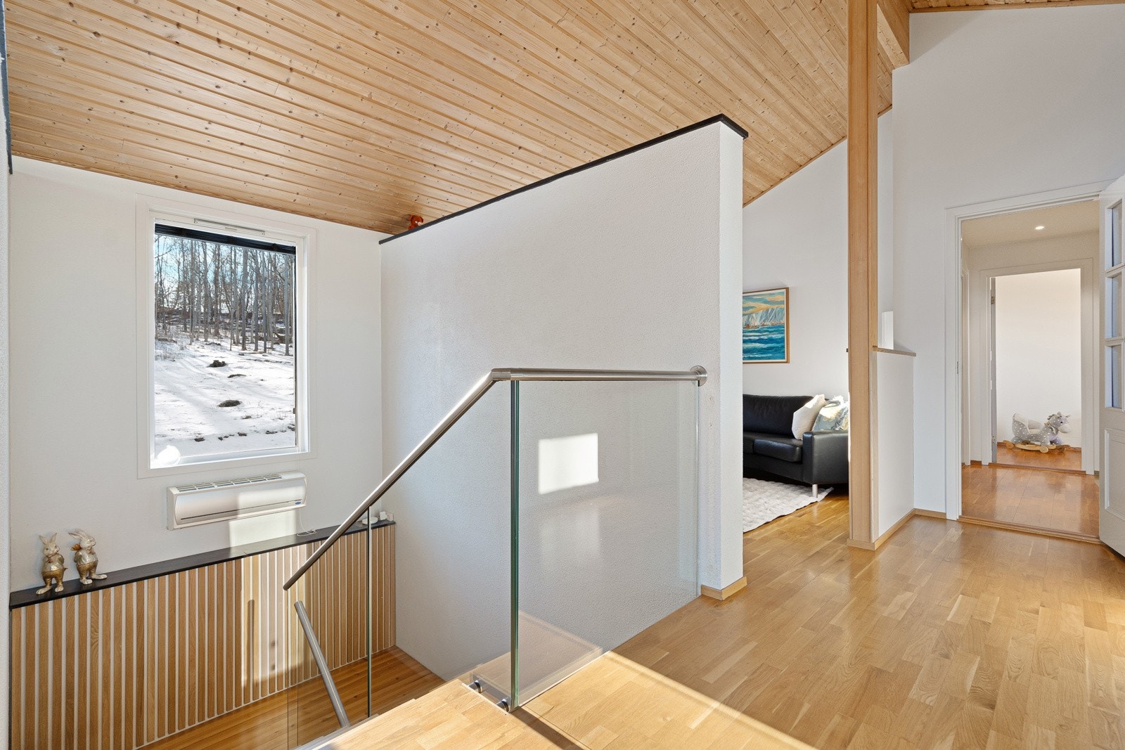 Lyst og romslig trappeløp med glassrekkverk mellom etasjene Galleribilde