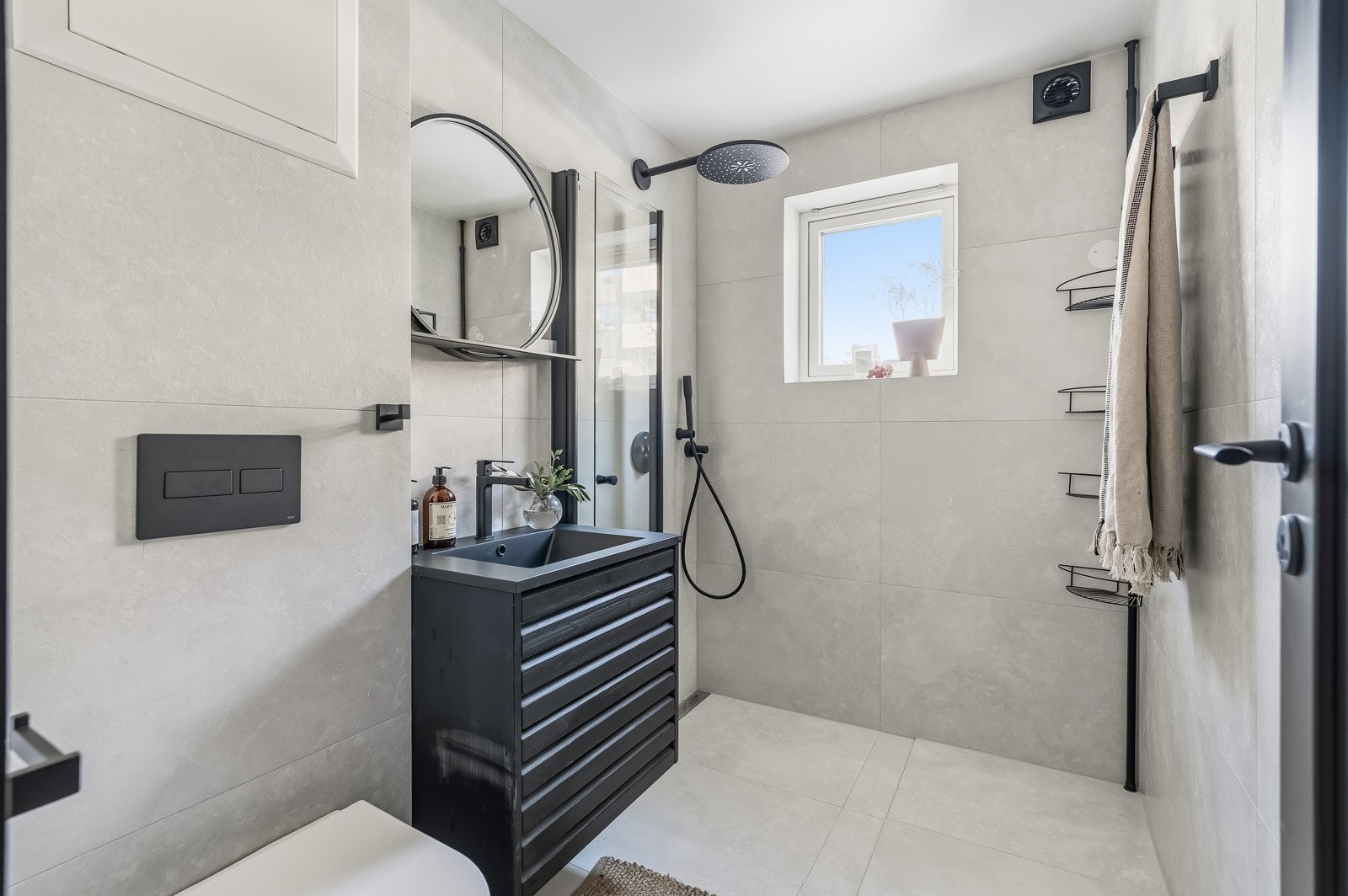 Moderne baderom i andre etasje med flislagte overflater og stilren innredning. Badet er utstyrt med dusj, vegghengt toalett og servantinnredning, samt elektrisk gulvvarme som gir god komfort. Galleribilde