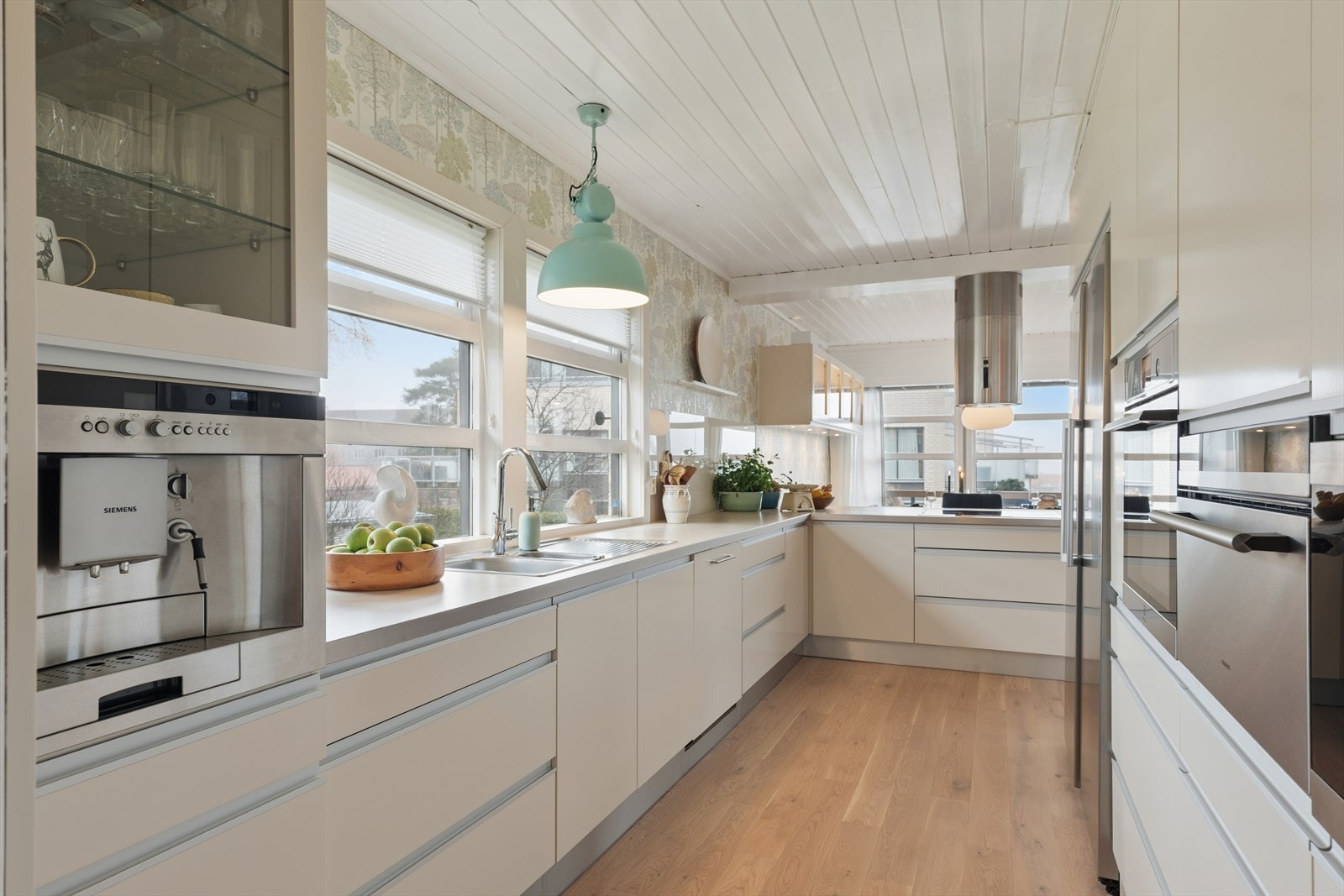 Kjøkkeninnredningen har glatte fronter og er utstyrt med integrert stekeovn, dampovn, mikroovn, oppvaskmaskin samt frittstående kjøleskap og fryseskap. Galleribilde