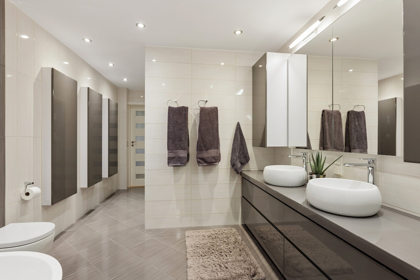 God skapplass med halvveis innfelte skap og store speilflater bidrar til et funksjonelt og stilrent baderom. Galleribilde