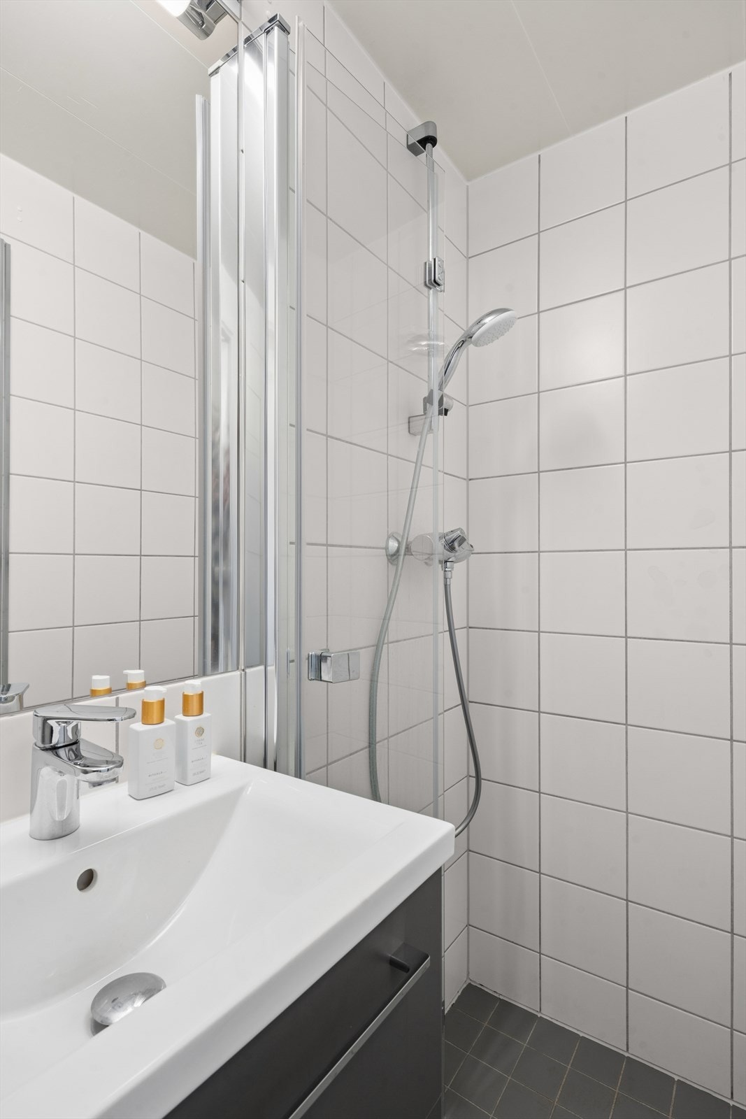 Badet er utstyrt med vegghengt toalett og dusjhjørne med foldedører i glass. Galleribilde