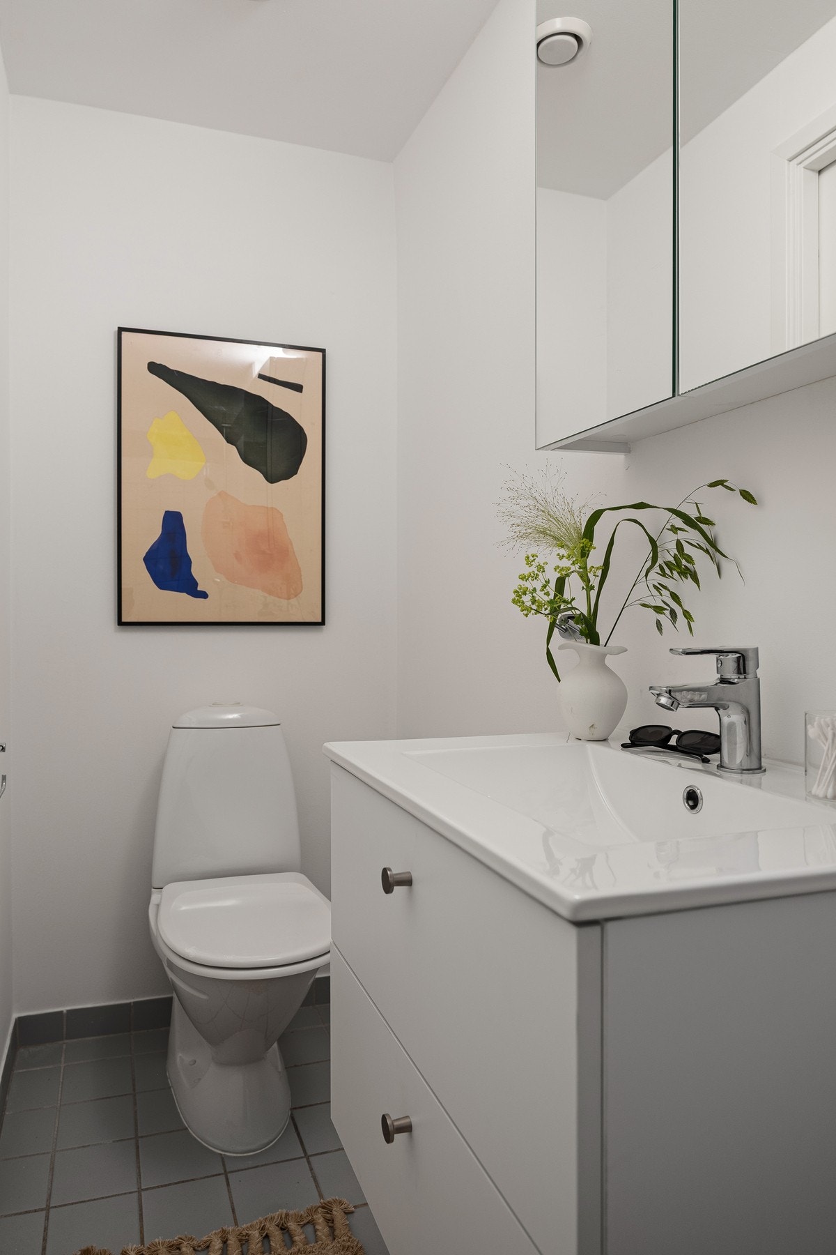 Badet inneholder servant med underskuffer, speilskap, dusjhjørne og toalett. Galleribilde