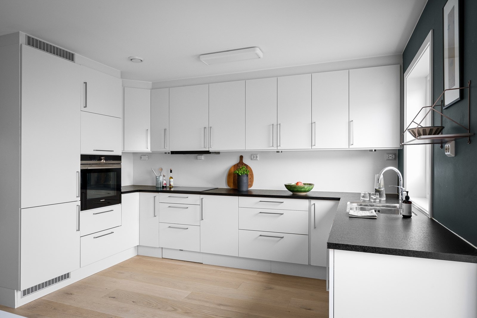 Optimalt oppsatt kjøkken for maksimal oppbevaring, funksjonalitet og bespisning. Spotter under overskap. Rikelig med naturlig lys via vinduer og terrassedør. Stilrent og enkelt å tilføre eget interiør. Galleribilde