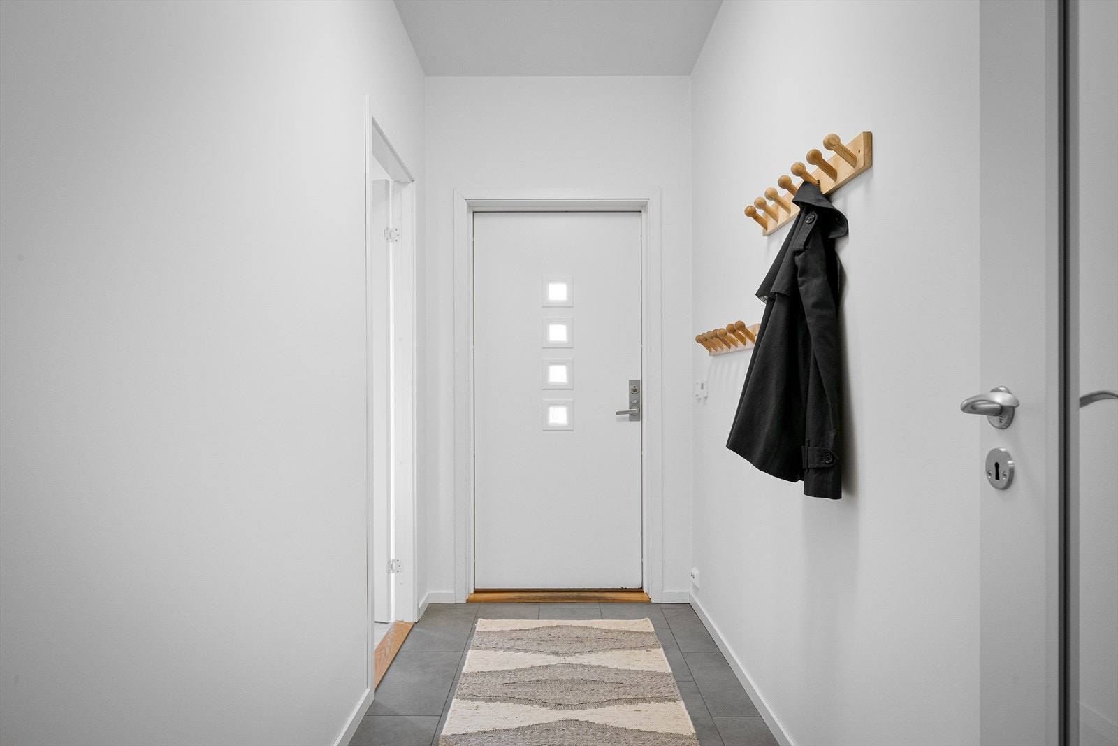 Gang med fliser som tåler våte sko, og lun, vannbåren varme i gulvet. Rikelig med oppheng og plass til kommoder e.a. Skyvedørsgarderobe videre inn i hall. Galleribilde