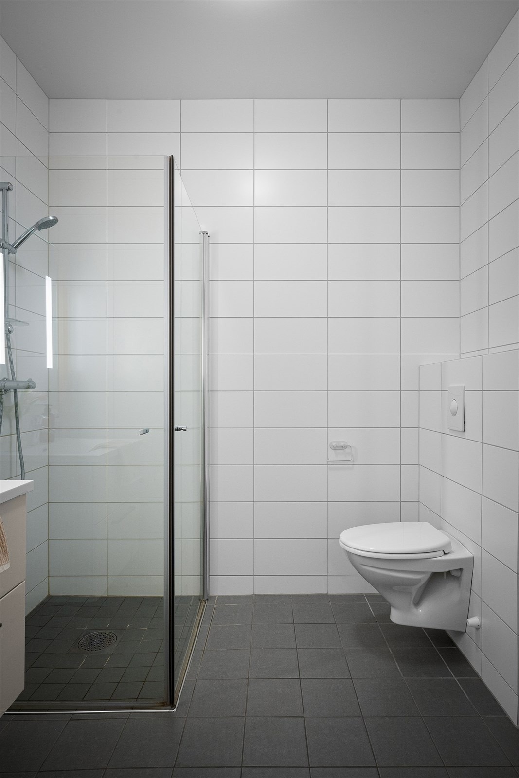 Hylle over wc for evt grønn plante og noen te-lys som gir fin atmosfære. Dusjvegger kan foldes sammen for bedre romfølelse. Ett av to baderom med vannbåren, lun varme og gode fasiliteter. Tidløst og stilrent gjør det enkelt å tilføre eget interiør. Galleribilde