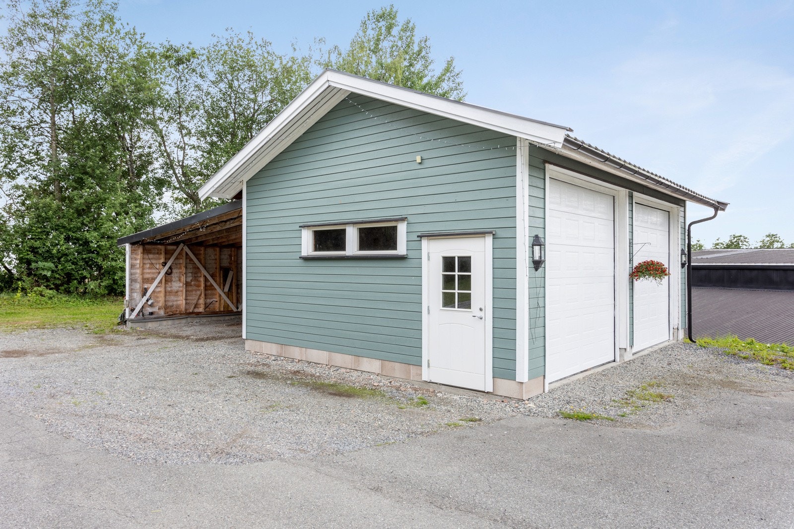 Høy dobbeltgarasje med tilhørende carport med plass til to biler til. Galleribilde