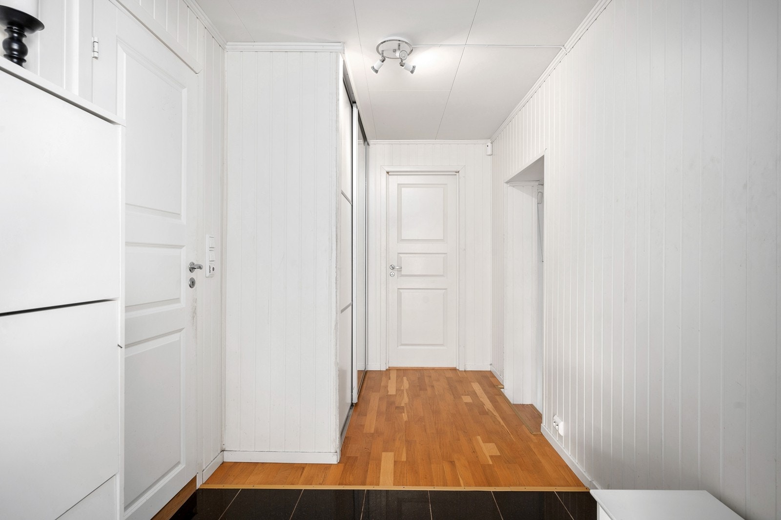 Entréen har adkomst til bad, trapp og soverom 1. Det er delvis fliser og trestavs parkett på gulvet og panelplater på vegger. Galleribilde