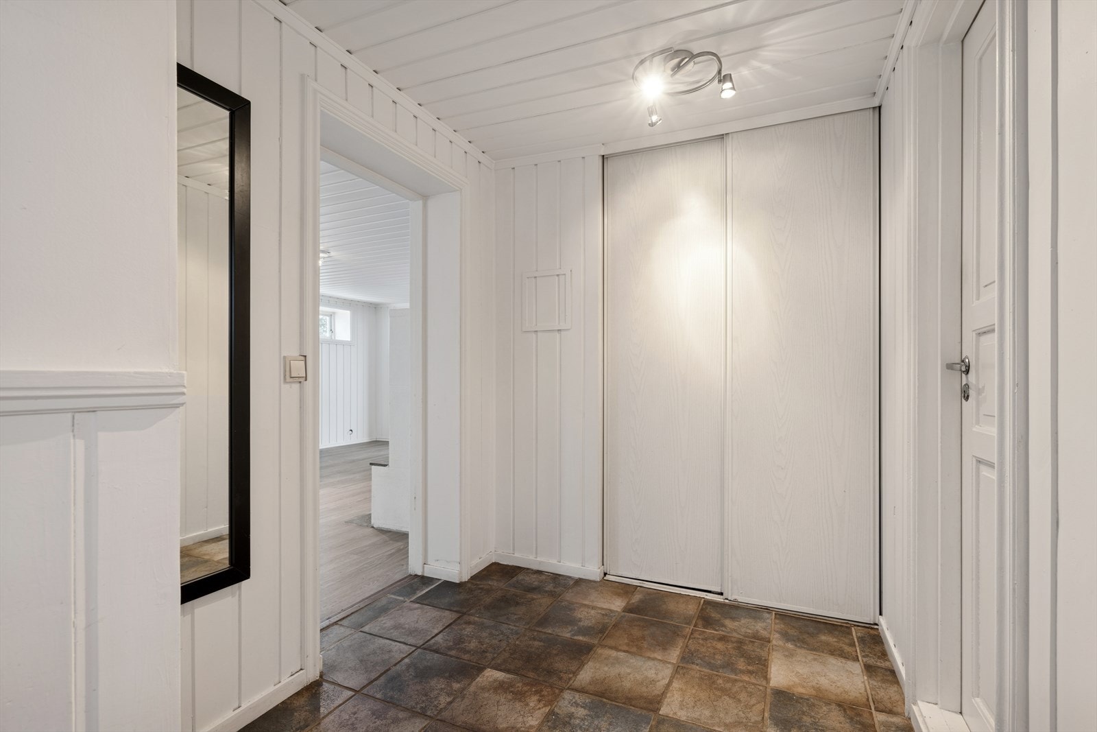 Entréen leder videre inn i boligens oppholdsrom og til badet. I enden av gangen er det en praktisk garderobeløsning. Galleribilde