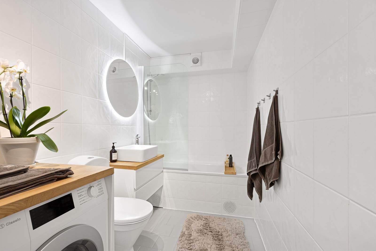 Eldre flislagt bad med gulvvarme. Utstyrt med badekar, innfellbare dusjdører, servantskap, opplegg for vaskemaskin, naturlig avtrekk og wc. Galleribilde