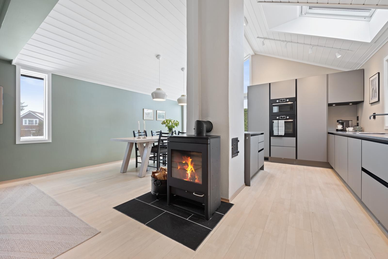 Hyggelig kjøkken med peisovn, store vindusflater og mønt himling med ekstra god takhøyde - opp til ca. 3,5 meter på det høyeste, samt takvinduer som gir fint lysinnslipp i rommet. Galleribilde