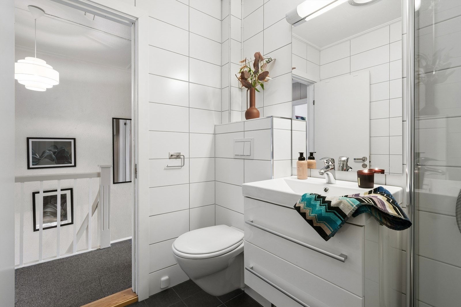 Badet er innredet med vegghengt toalett og en stilren servant med skuffer som gir god oppbevaringsplass. Galleribilde