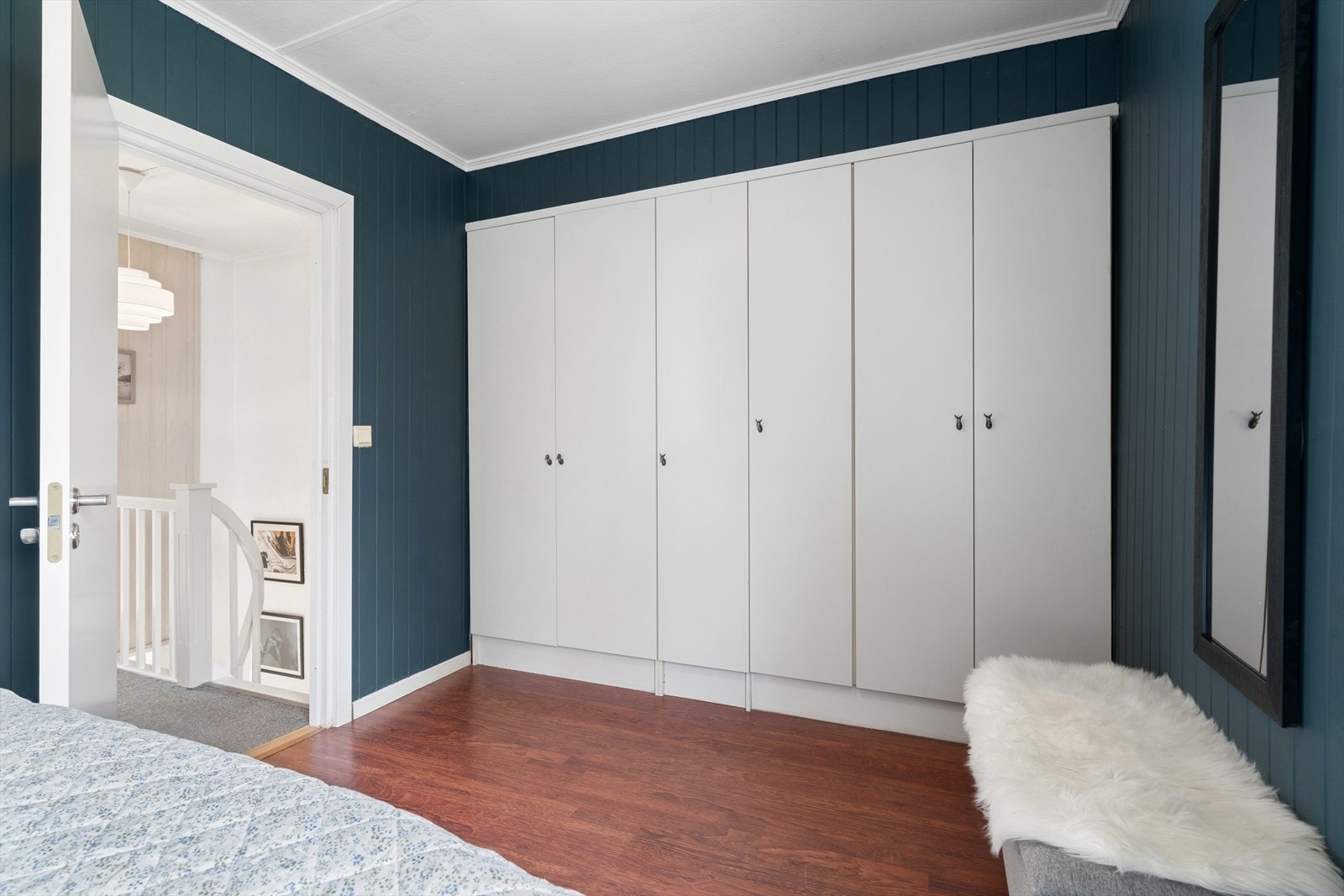 Romslig hovedsoverom med god lagringsplass takket være en hel vegg med innebygde garderobeskap. De høye, hvite frontene gir et rent og ryddig uttrykk, samtidig som de utnytter rommets volum svært godt. Galleribilde