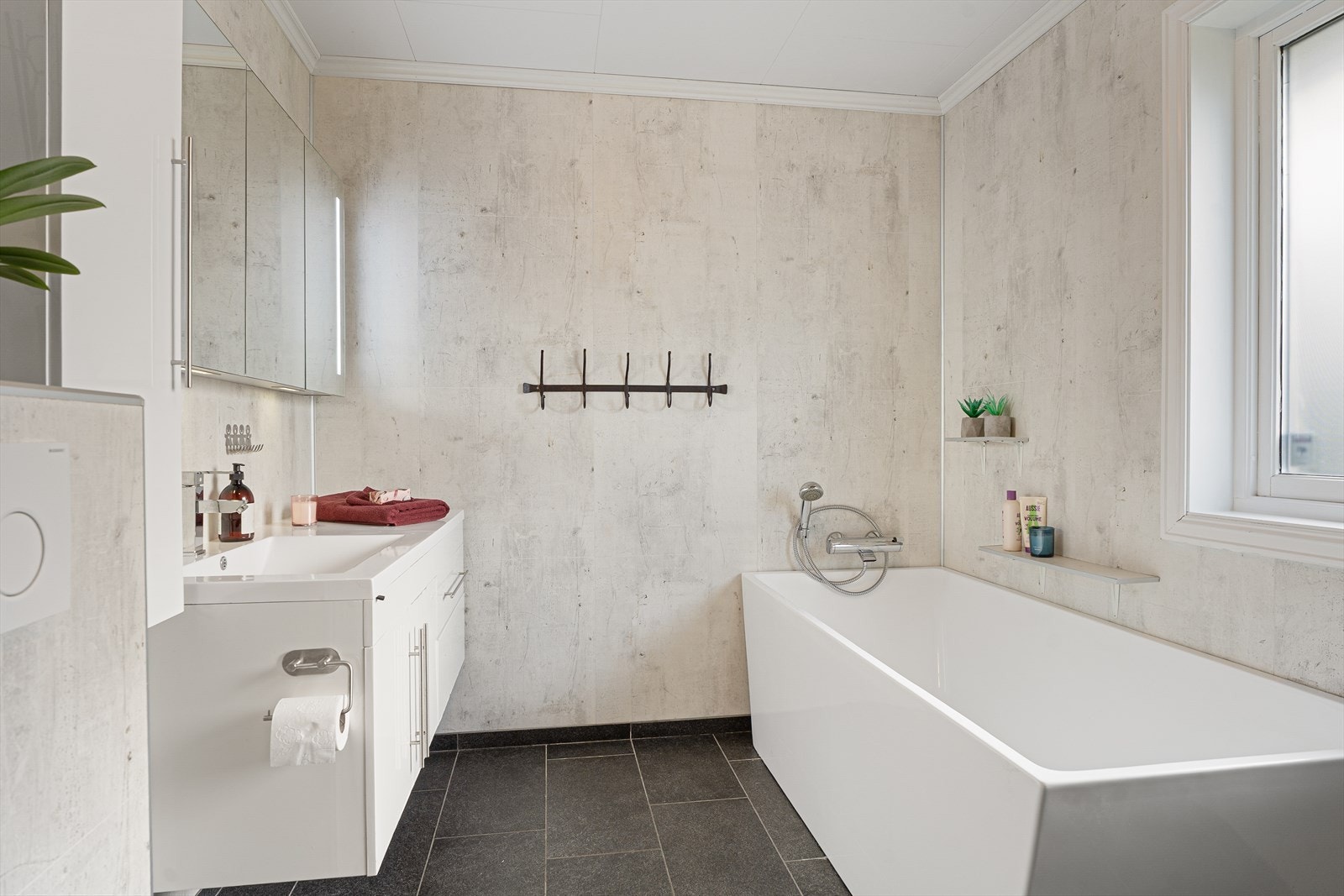 Lyst og pent bad i 1. etasje med baderomsplater på veggene, fliser på gulvet og himling med malte plater - badet ble oppgradert i 2016 med nytt inventar samt nye overflater på vegger og gulv Galleribilde