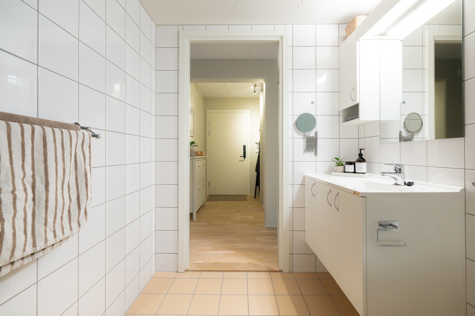 Videre er badet innredet med servant på underskap, speil med belysning og overskap. Galleribilde