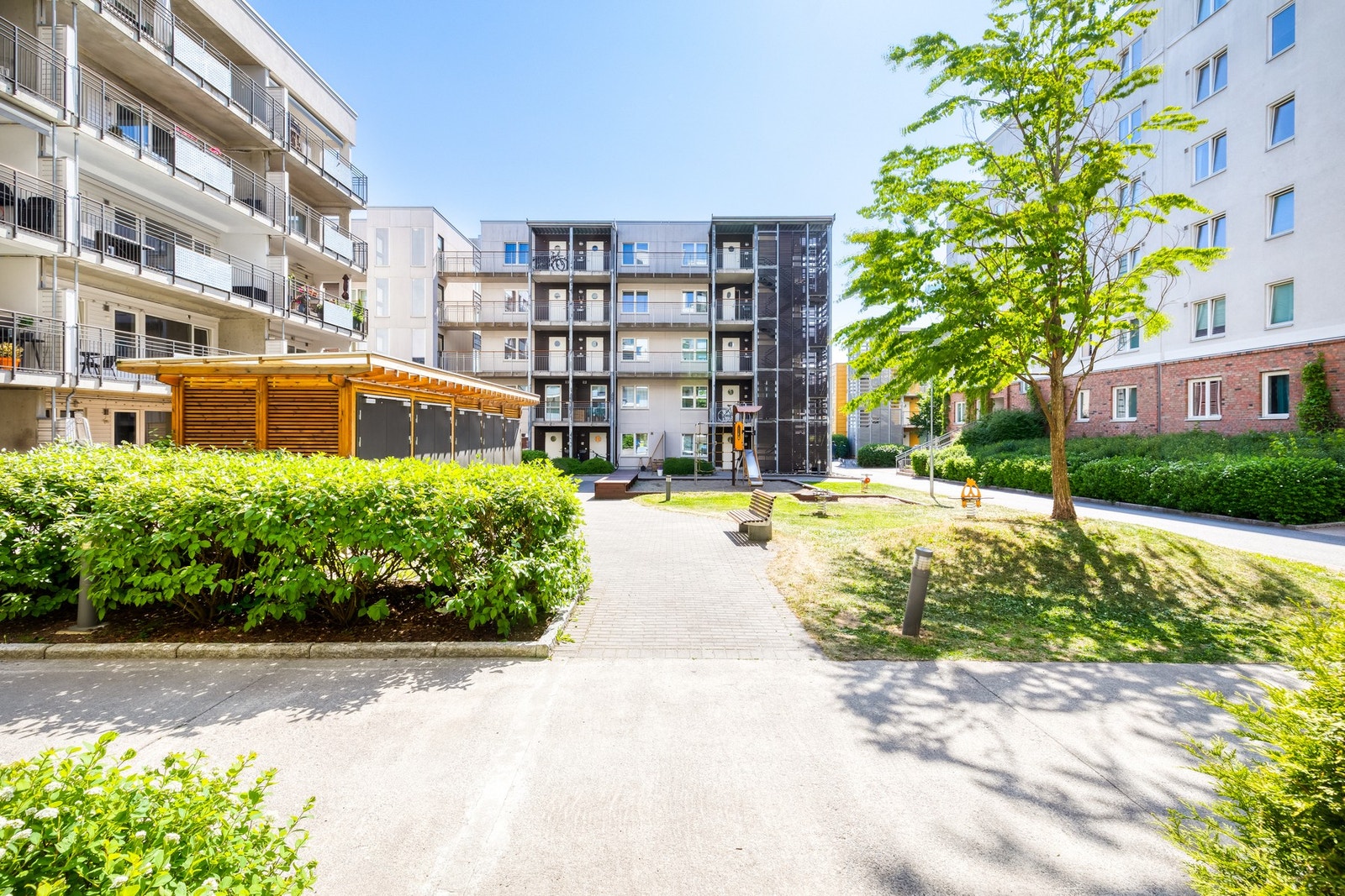 Bilfrie og pent beplantet fellesarealer mellom bebyggelsen på boligfeltet. Galleribilde