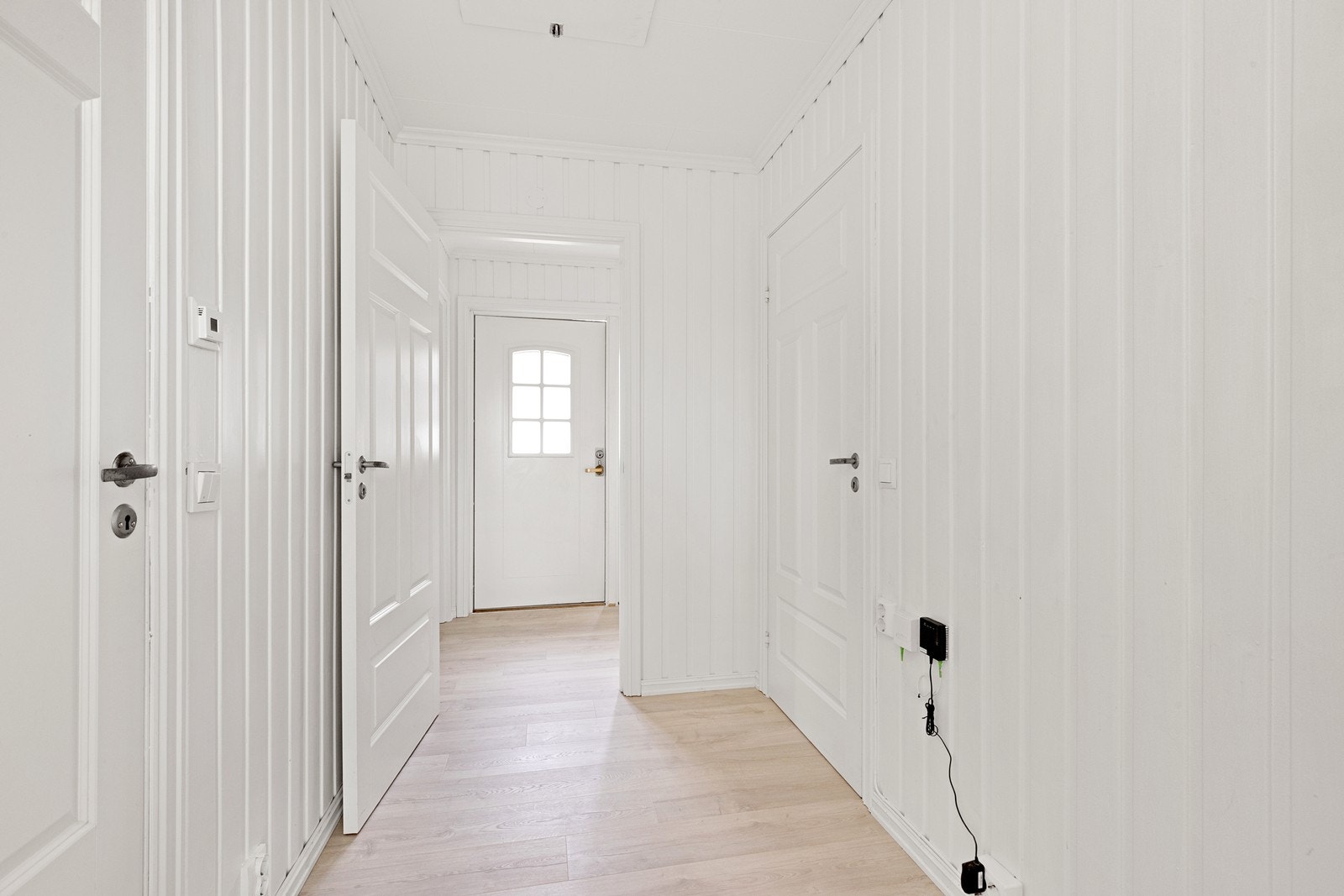 Hvite fyllingsdører og panelvegger gir en lys og innbydende entré. Galleribilde