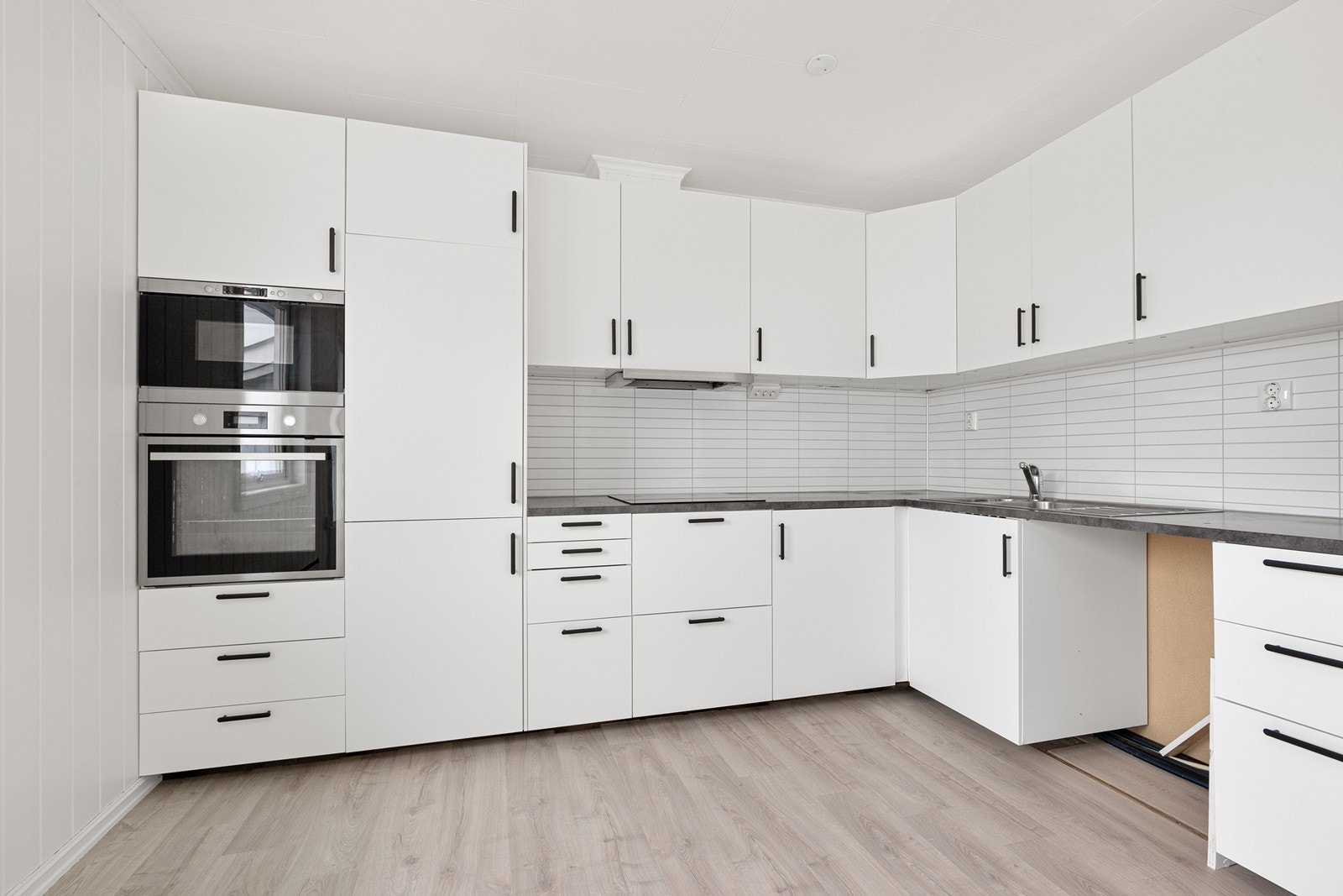 Kjøkkenet er utstyrt med induksjonstopp og komfyr, med Kitchenboardplater mellom benkeplate og overskap. Galleribilde