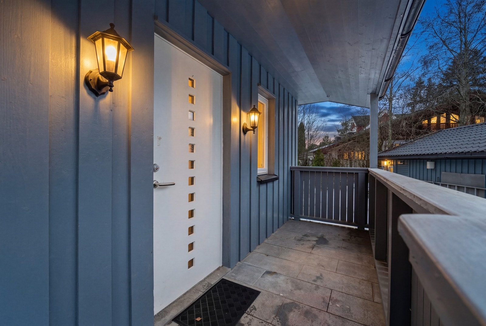 Eneboligen har et pent, overbygd inngangspart med klassisk utebelysning og skiferlagt dekke. Galleribilde