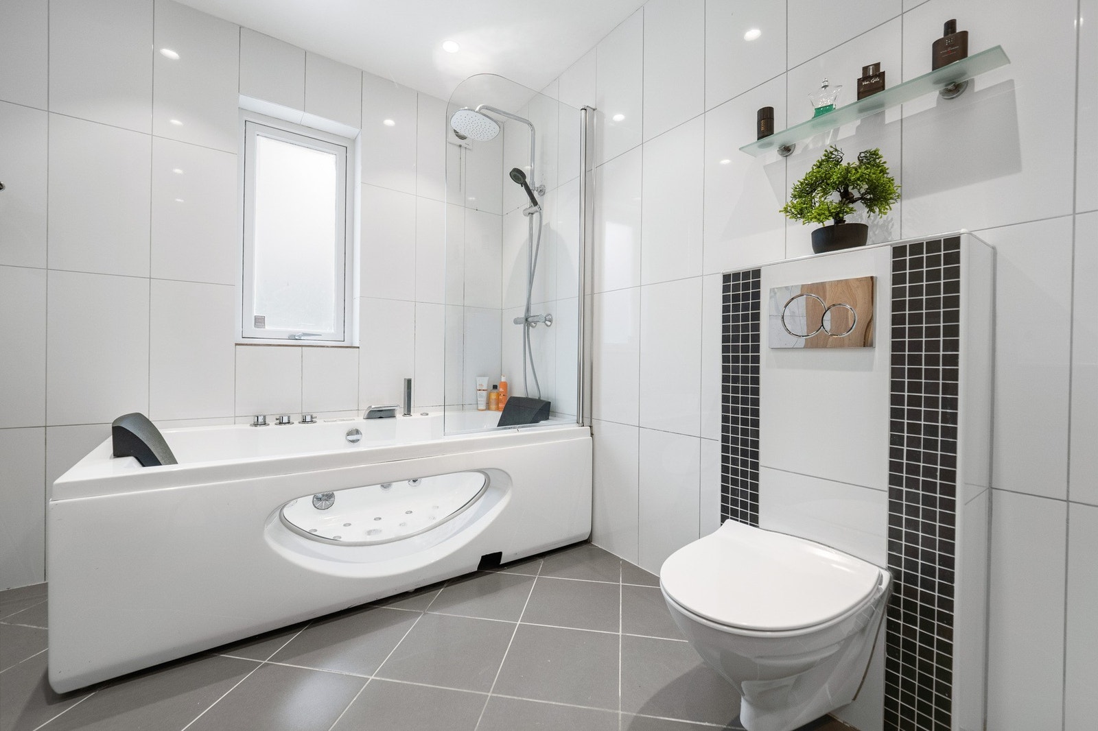 På veggen over et moderne badekar er det montert regnfallsdusj. Galleribilde