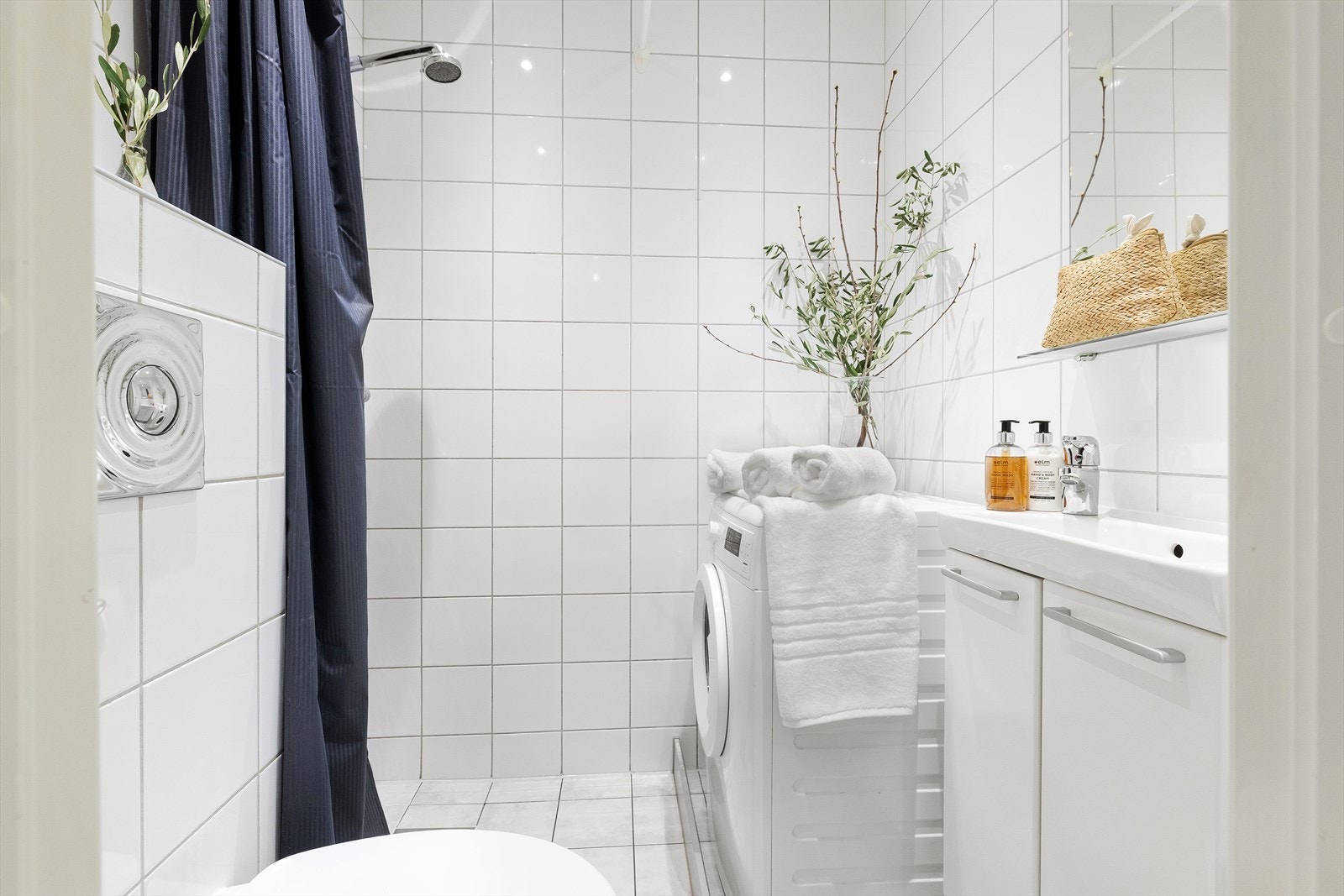 Det er opplegg for vaskemaskin og baderommet har naturlig ventilering. Badet er utstyrt med servant, veggmontert toalett og dusjforheng. Galleribilde