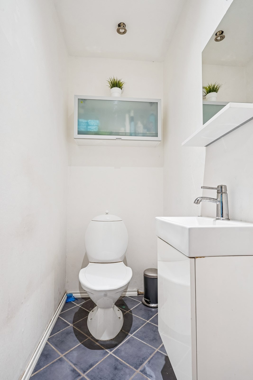 Praktisk, separat toalettrom med flislagt gulv, servant med underskap og speil. Galleribilde