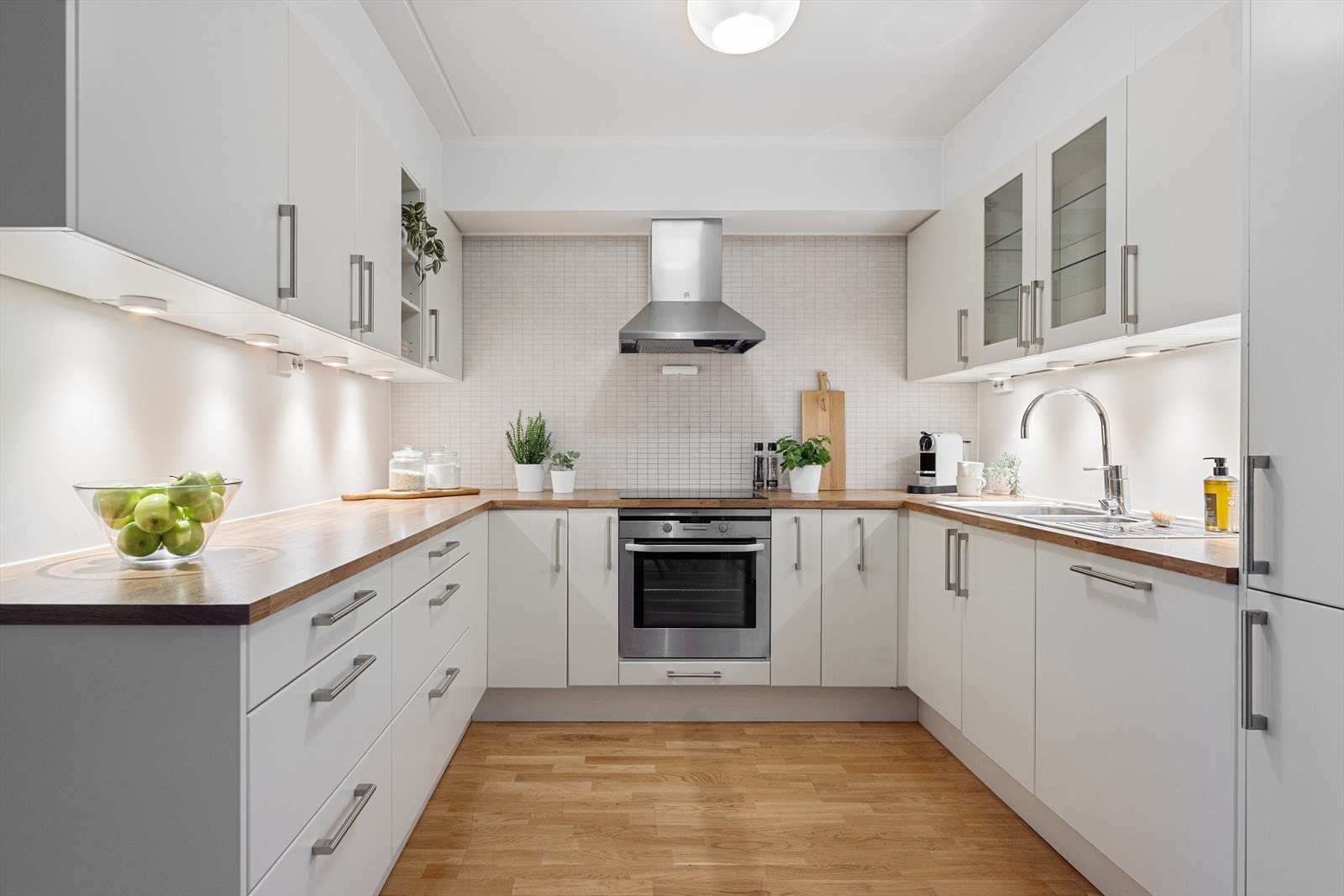 Kjøkkenet har en åpen løsning mot stue og spisestue. Innredningen er fra Norema med hvite, glatte fronter og rikelig med både over- og underskap som gir god oppbevaringsplass. Galleribilde