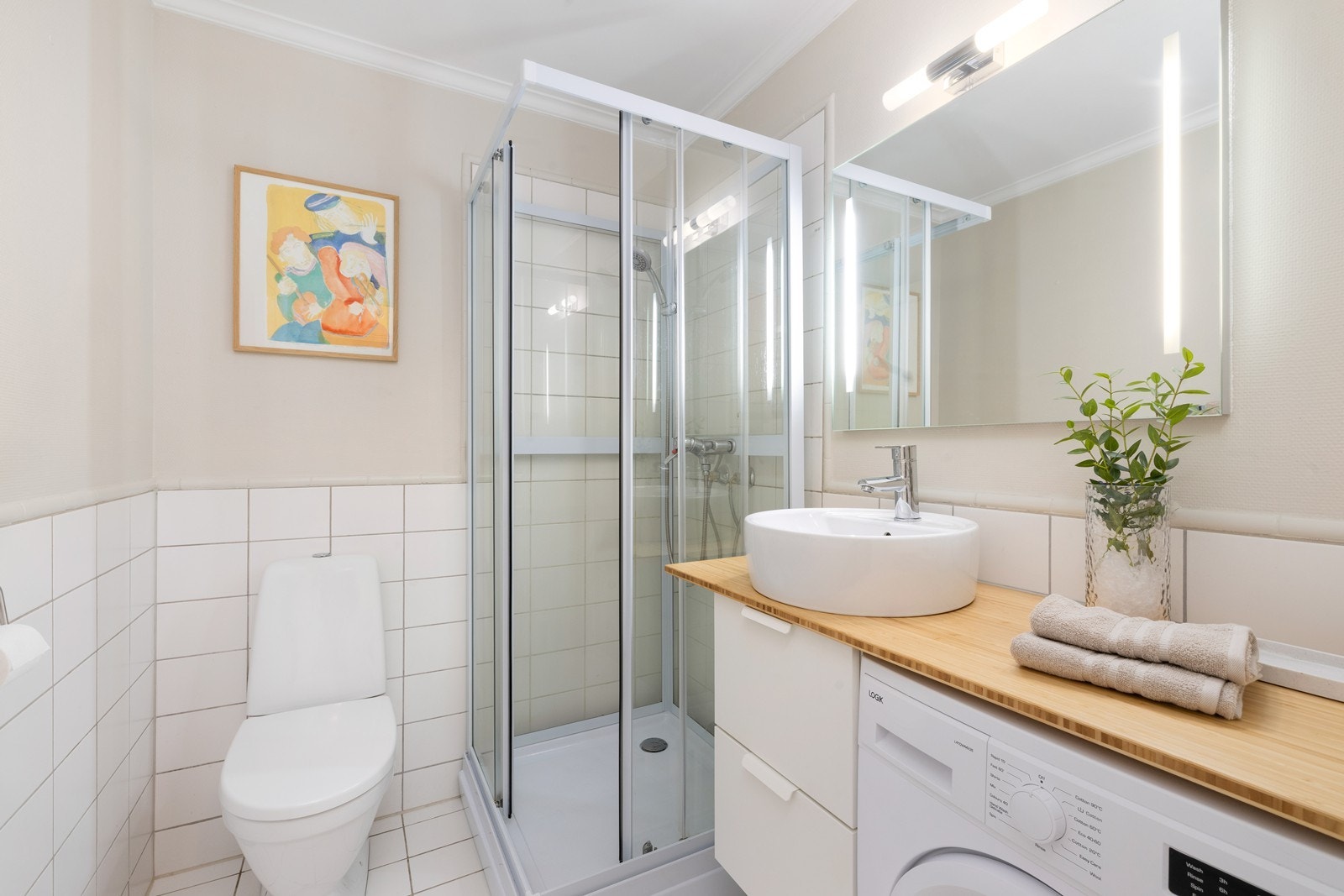 Bad som inneholder wc, servant, dusjkabinett og opplegg for vaskemaskin Galleribilde