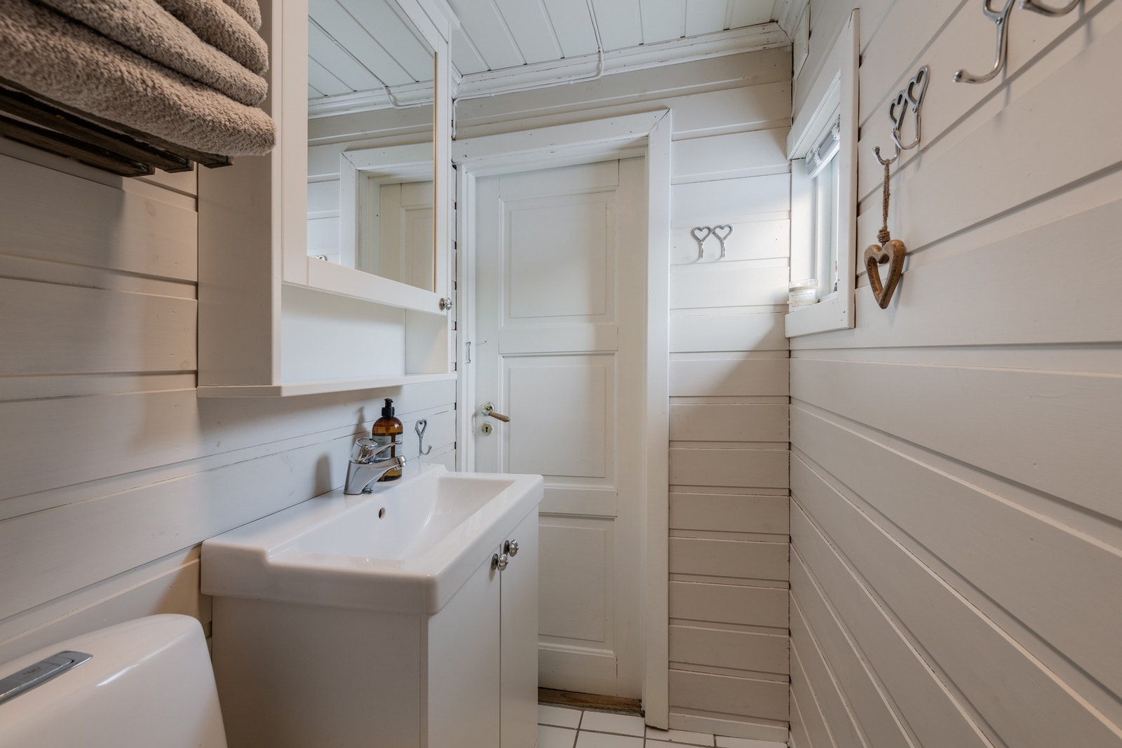 Badet har vegger og himling med malt panel, gulv og vegger i dusj er flislagt Galleribilde