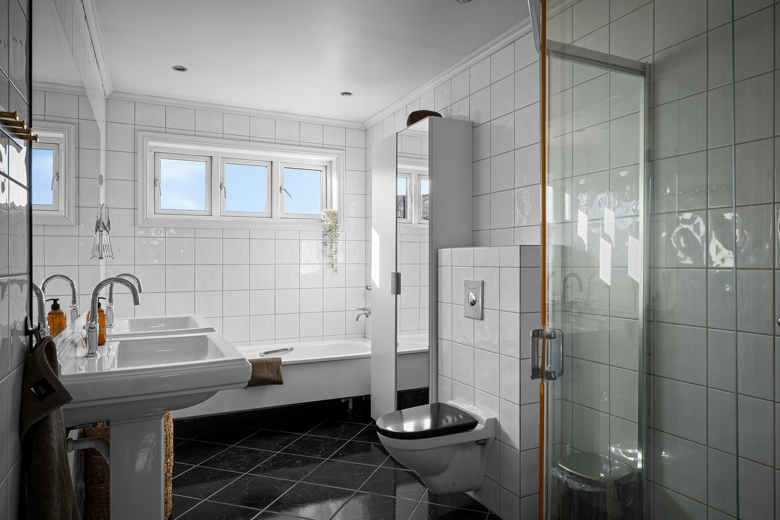 Badet har vannbåren varme i gulvet, vegghengt toalett og et dusjhjørne med glassdører. Galleribilde