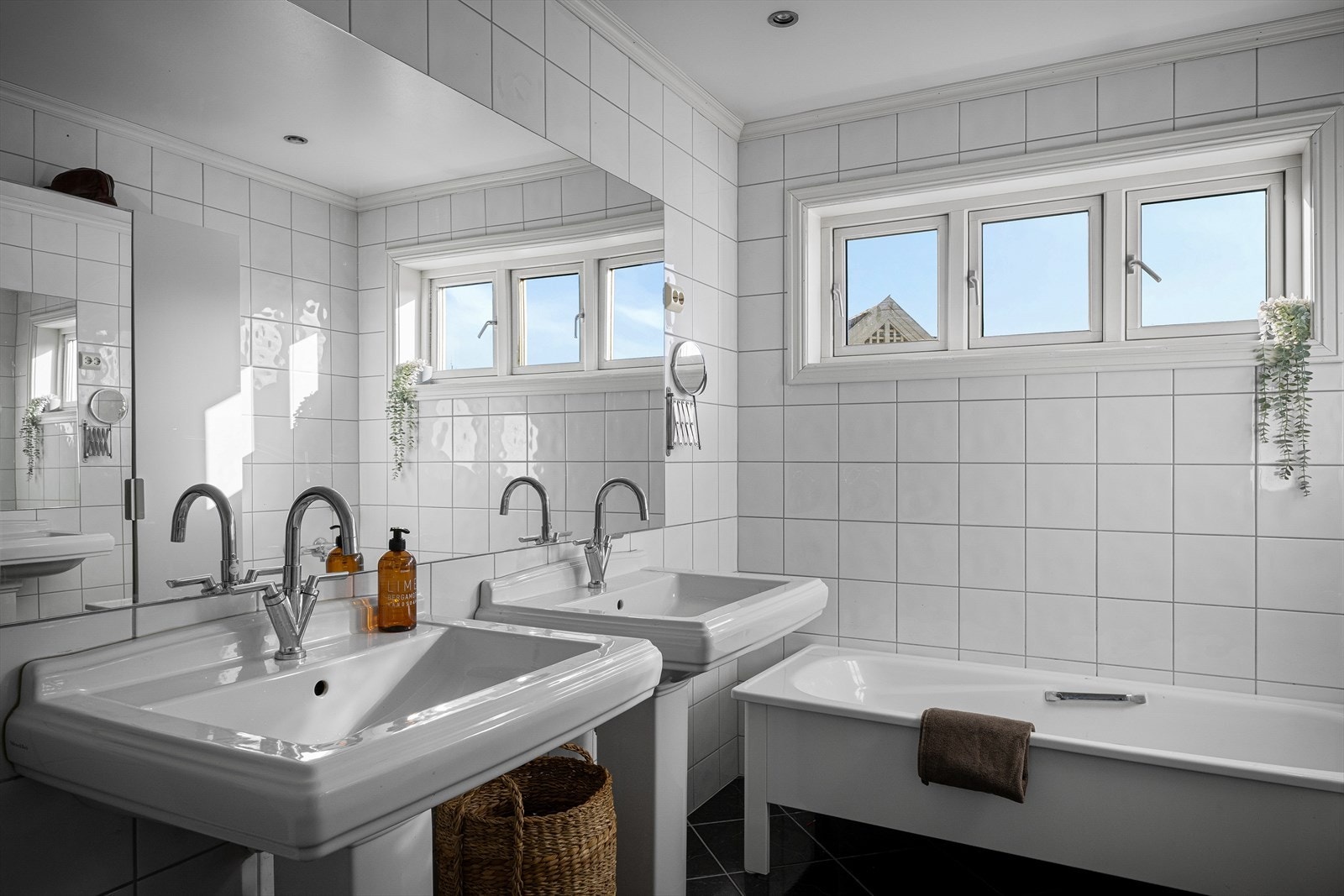 Stort bad i andre etasje med fliser på gulv og vegger. Rommet har to stilrene søylevasker og badekar. Galleribilde