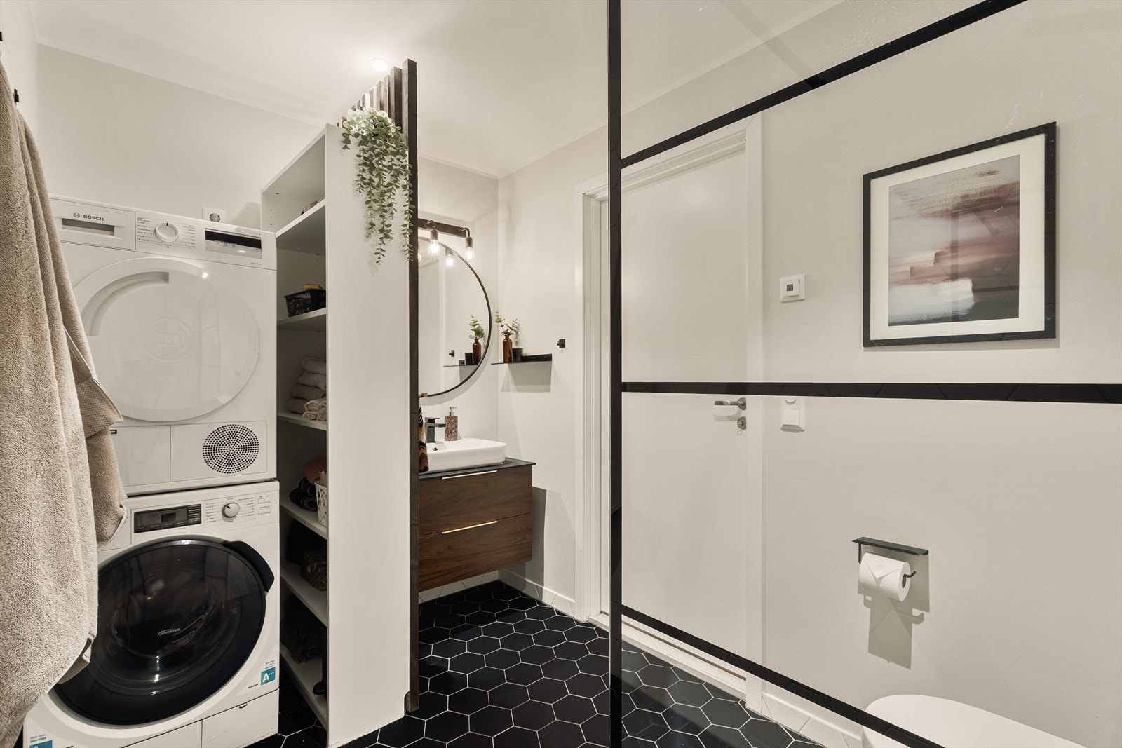 Badet er innredet med servant med underskap, veggmontert toalett og dusj med glassvegg. Det er opplegg for vaskemaskin. Galleribilde