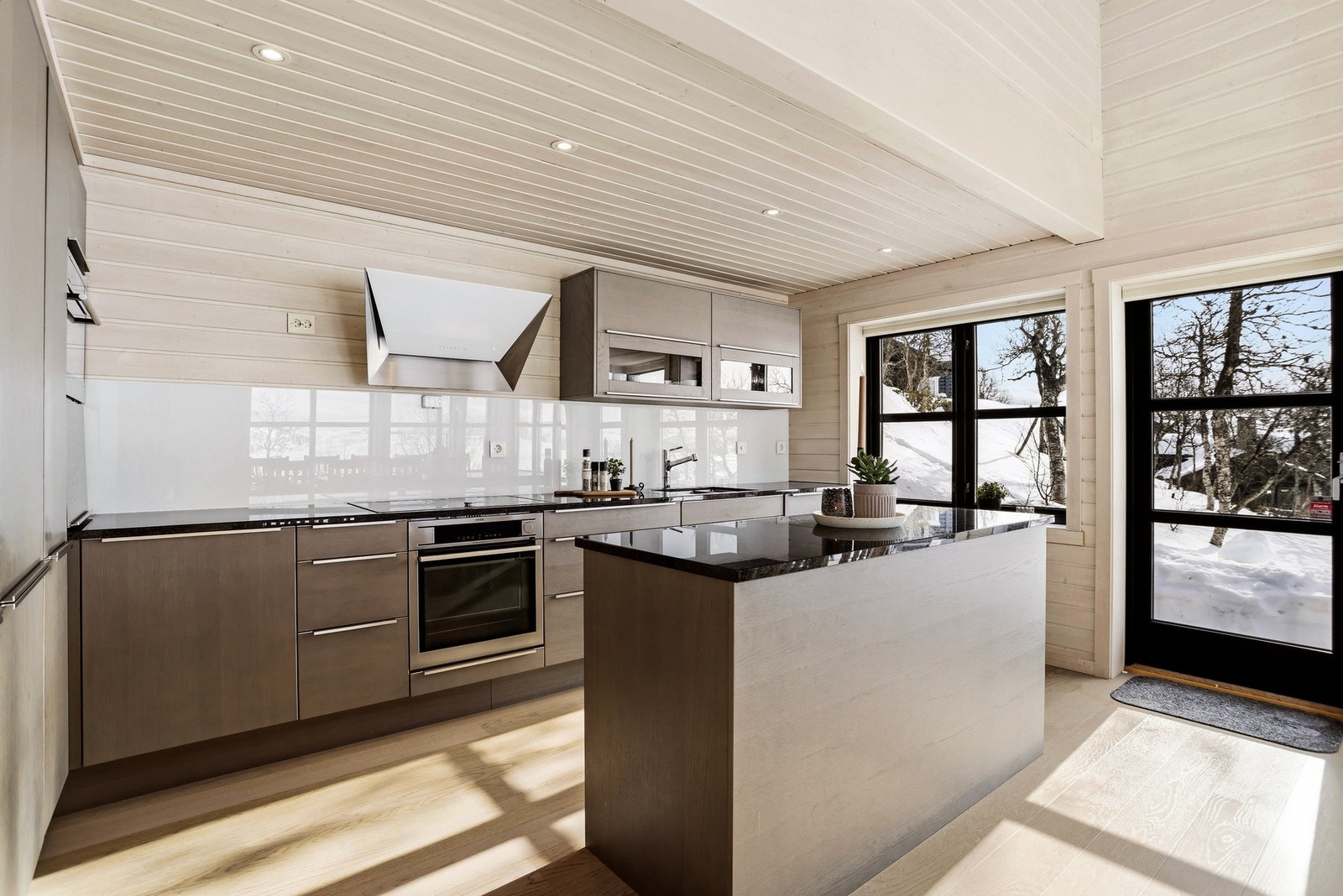 Kjøkkenet fremstår eksklusivt med benkeplate i granitt/stein og integrerte hvitevarer fra AEG, Gaggenau og Siemens Galleribilde