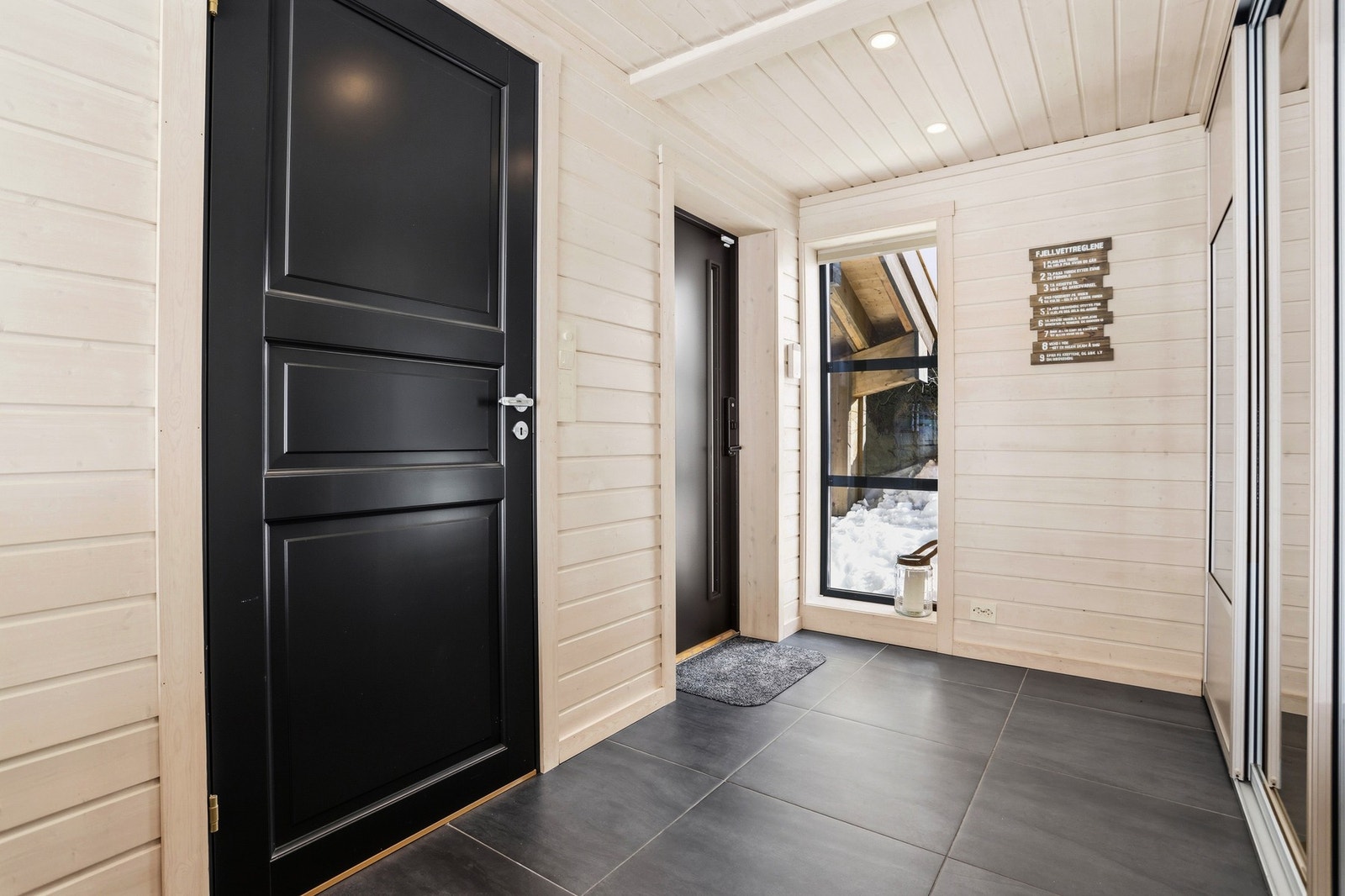 På gulv er det lagt moderne 60x60 flis i en mørk farge. Her er det også varmekabler i gulv, noe som gir en lun velkomst. Hytta har også eget inngangsparti/entré til gjestedelen Galleribilde