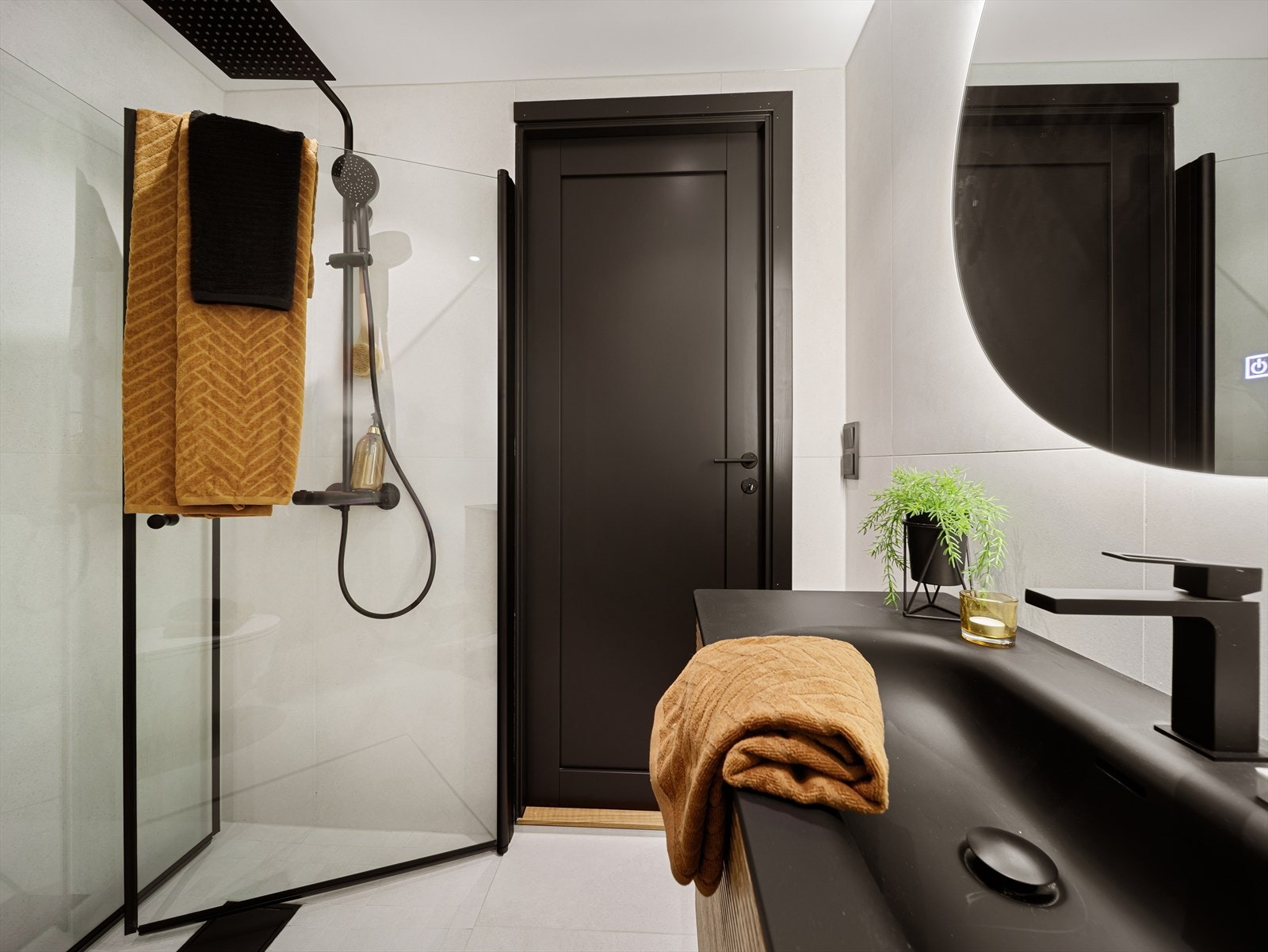 Badet er stilrent innredet med servant i innredning, veggmontert toalett og dusjhjørne med glassvegger. Galleribilde