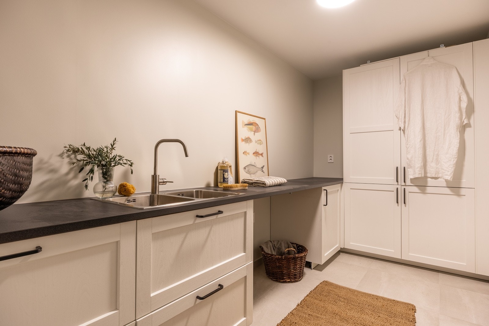 Separat vaskerom med god benkeplass, oppbevaringsmuligheter i skap, og opplegg for både vaskemaskin og tørketrommel i egen nisje. Galleribilde