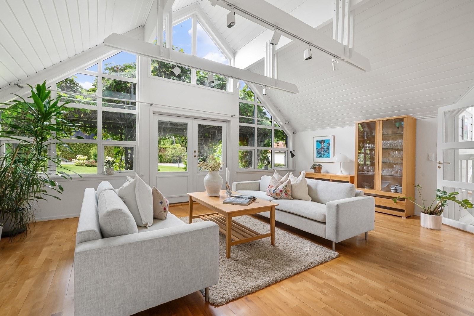 Veggene og skråhimlingen er malt opp i stilrent hvitt, og stuen har gyllen, tostavs parkett i bøk på gulvet. Galleribilde