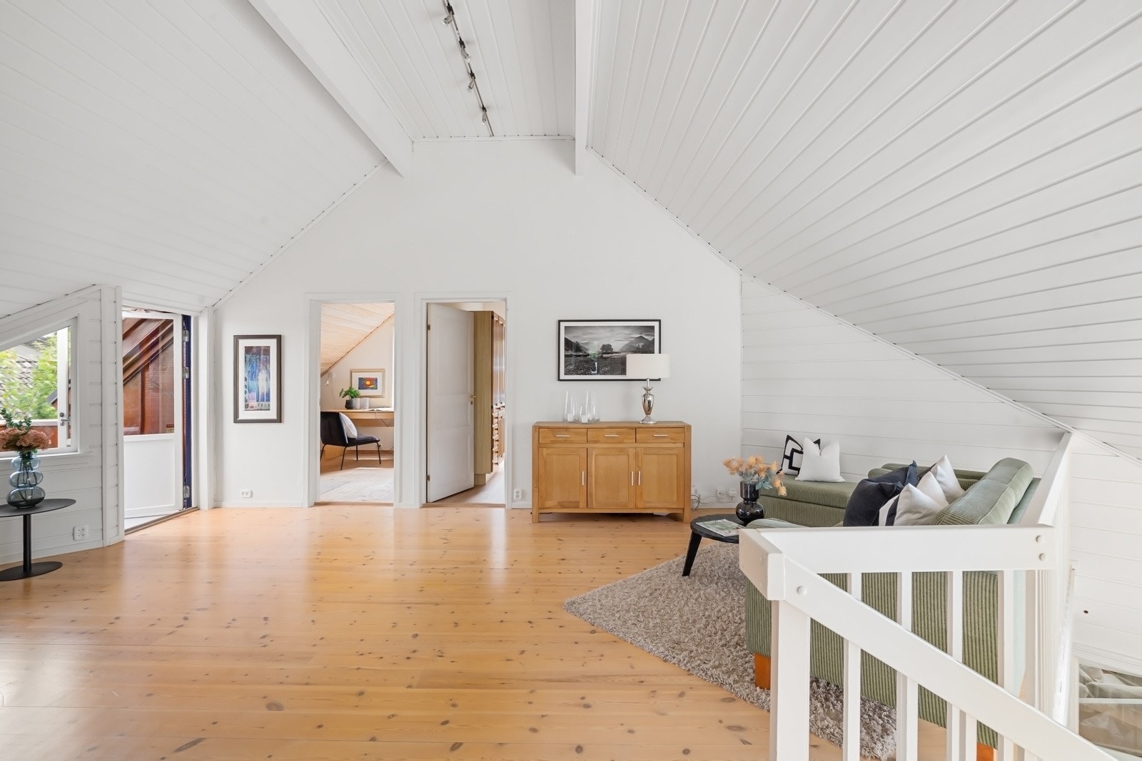 Loftstuen har hvitmalte overflater, ekstra god takhøyde og gyllent parkettgulv, og det er fin plass til en loungegruppe. Galleribilde