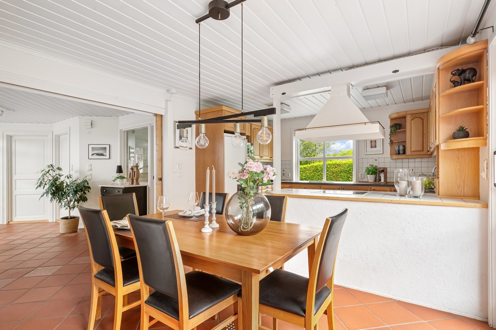 Rommet som utgjør kjøkken og spisestue har hvitmalte vegger og terracottafargede fliser på gulvet. Galleribilde