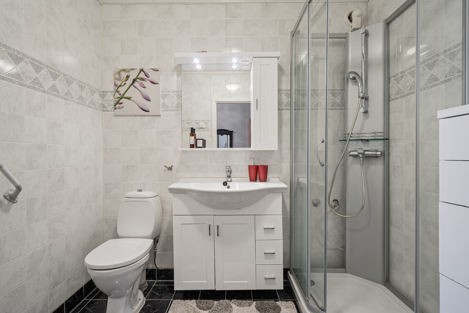 I boligen finner man to baderom. Dette badet ble modernisert i 2010 og er innredet med mørke fliser på gulvet og lyse, sjatterte baderomsplater på vegg. I gulvet har man også varmekabler for ekstra komfort. Galleribilde