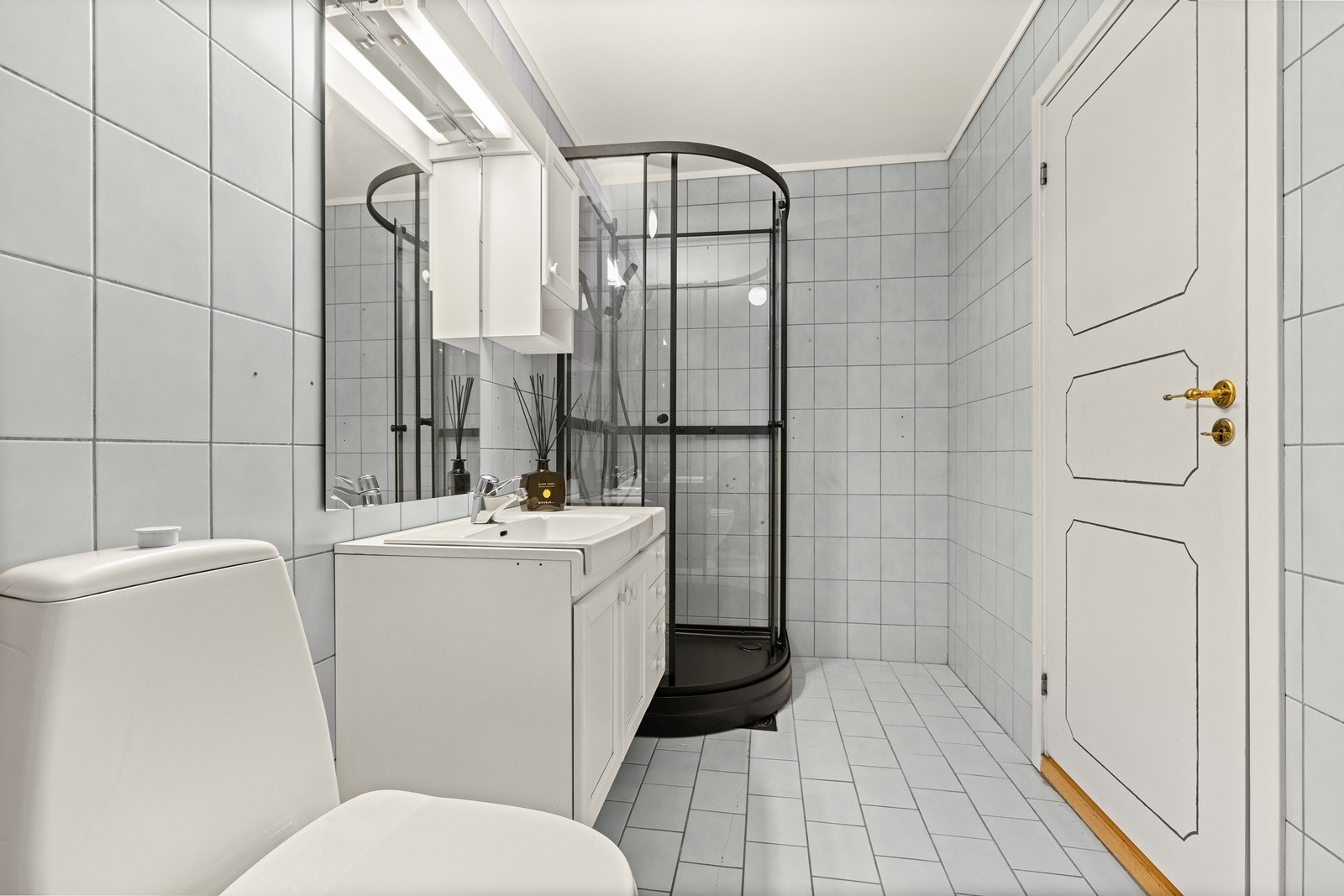 Badet er utstyrt med gulvmontert toalett, servant, servantskap, opplegg til vaskemaskin og skyllekar. Nyere dusjkabinett. Galleribilde